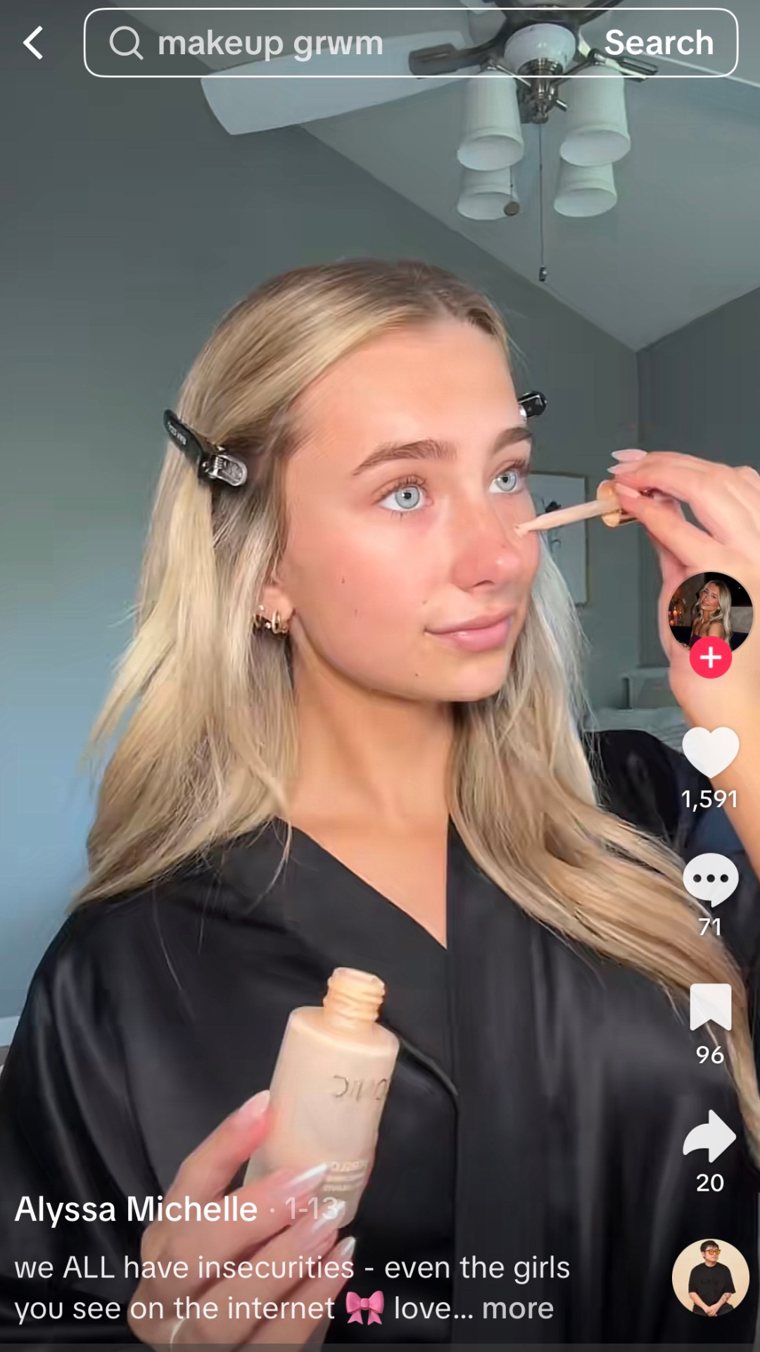 Blonde woman applying foundation with a sponge in a room, holding a foundation bottle.
