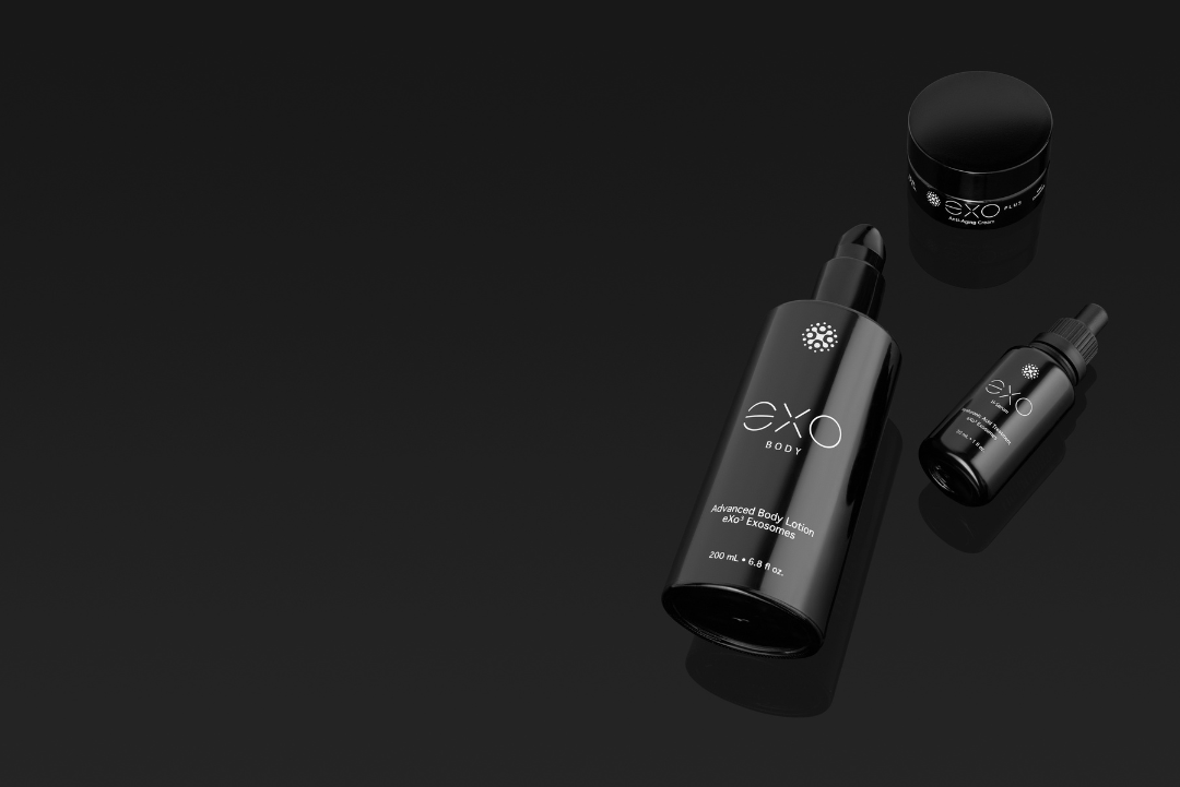 Black skincare bottles and jar on a black surface.