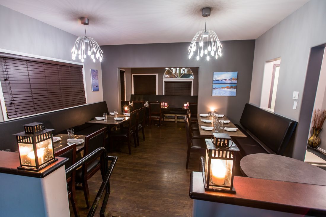 Cozy restaurant interior with tables, seating, dim lighting, and decorative lanterns.