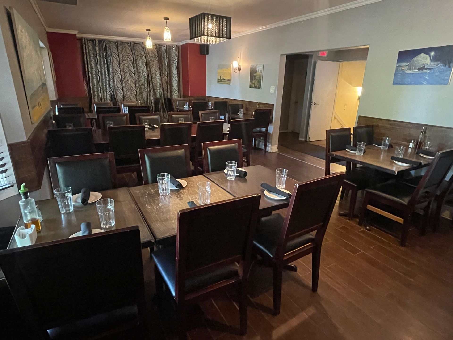 Cozy cafe interior with a table for two, copper chairs, plants, and shelves stocked with goods.