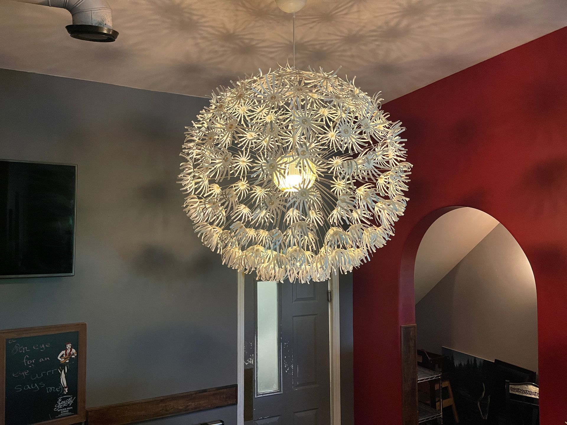 A bar interior with tables and stools, a screen for presentations, and dim lighting.