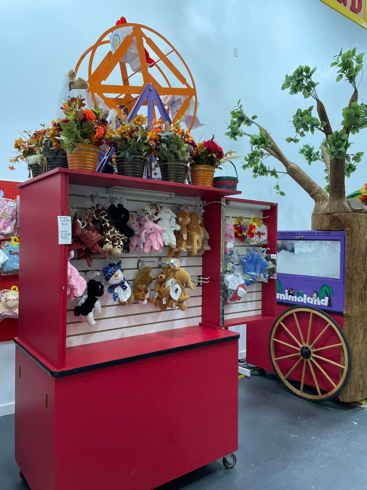 A red cart filled with stuffed animals and a ferris wheel in the background.