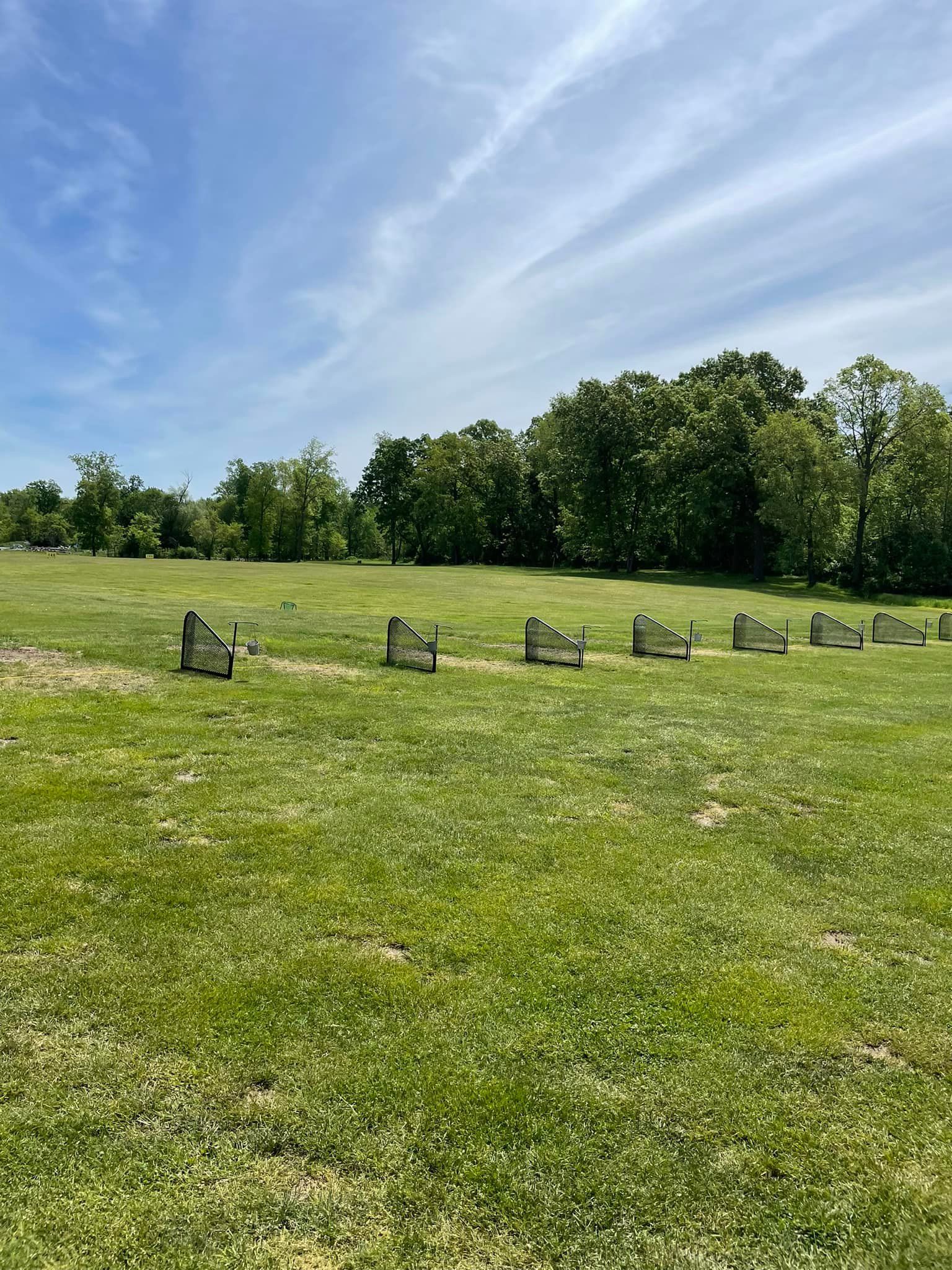A row of benches in a grassy field with trees in the background.