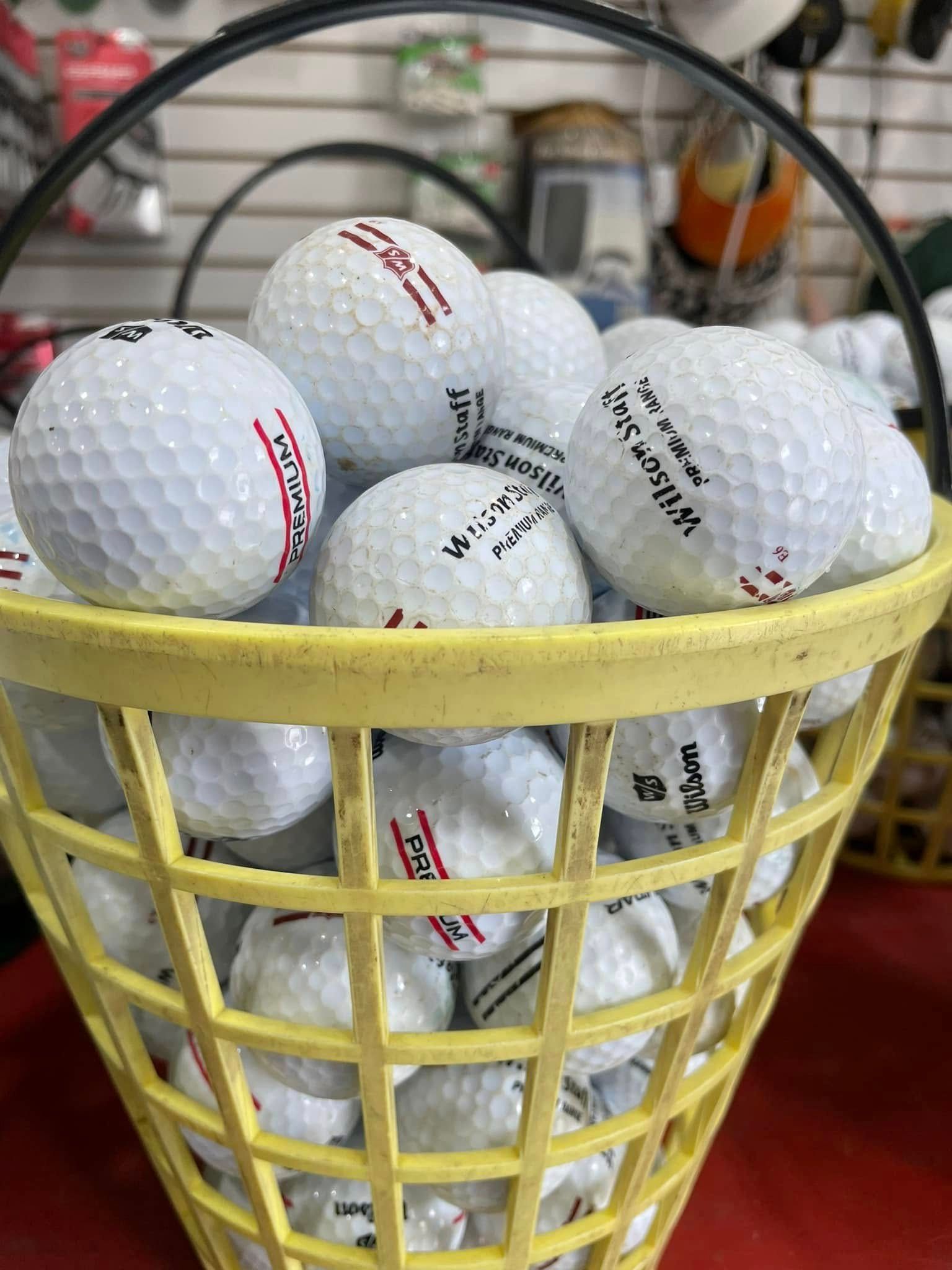 A yellow basket filled with white golf balls on a red table.