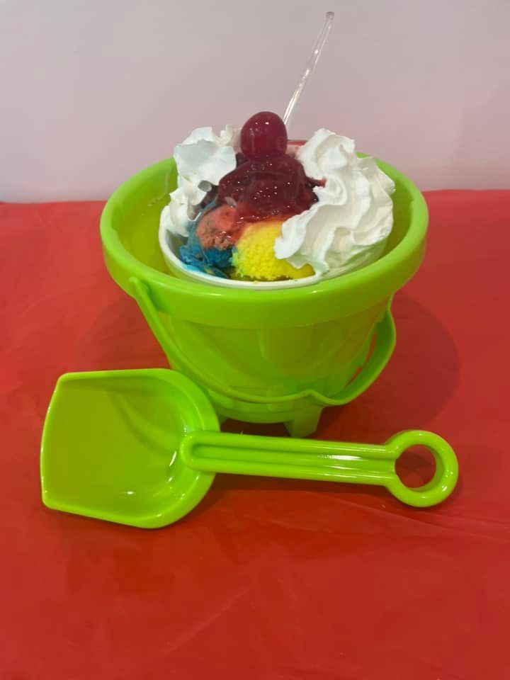 A green bowl of ice cream with whipped cream and a cherry on top.