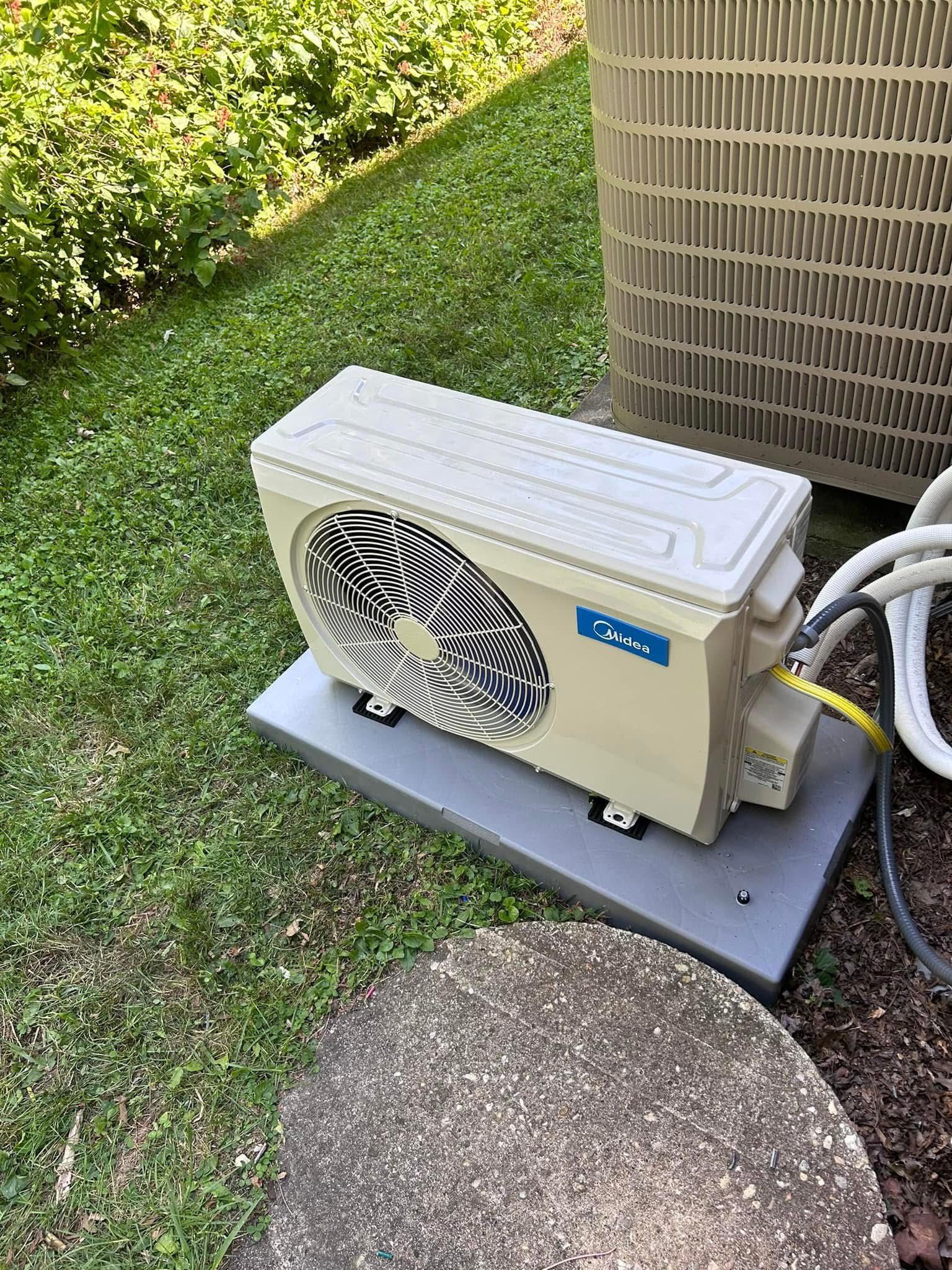Pool pump and heat exchanger on a concrete pad, near a grassy area and air conditioning unit.