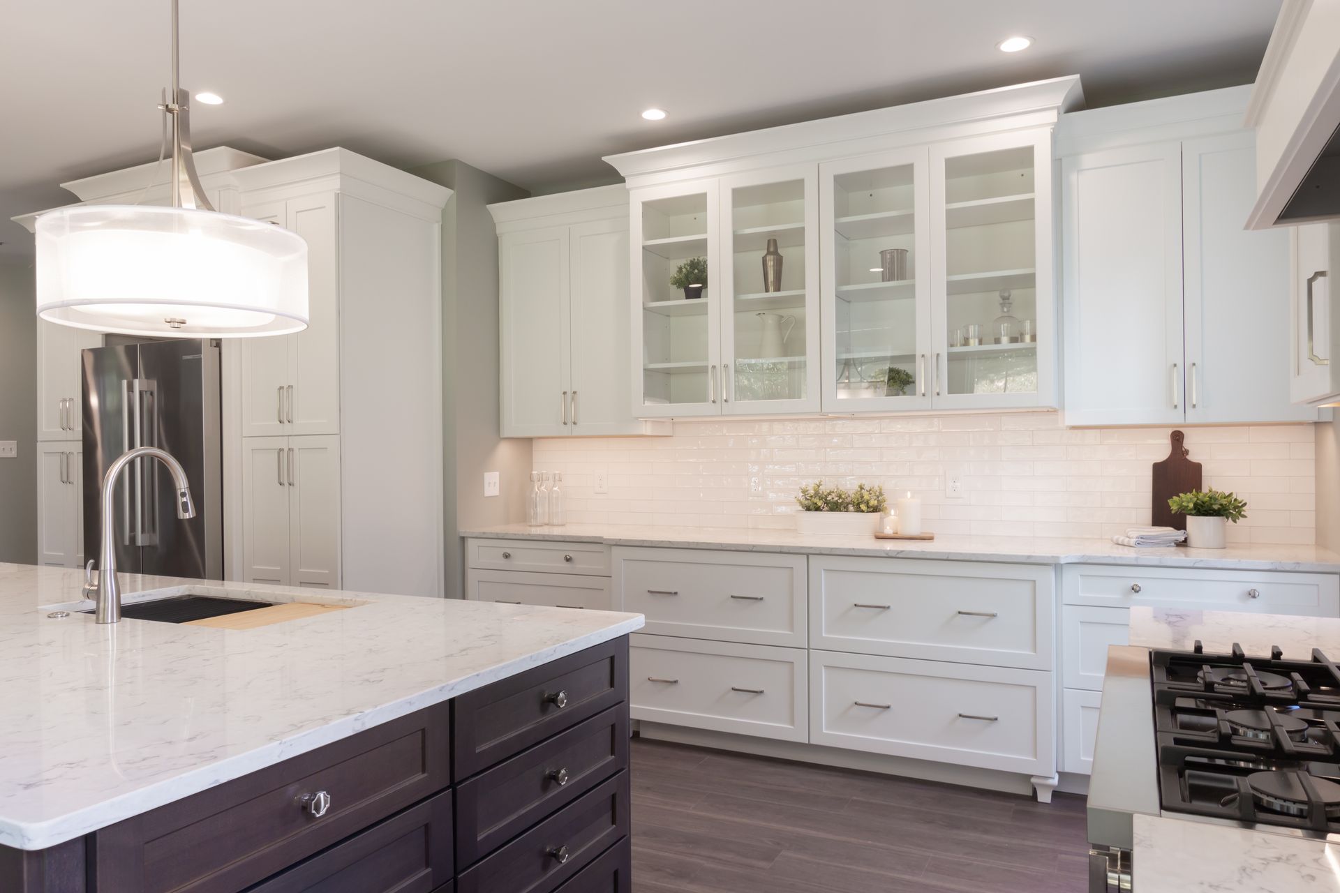 A kitchen with white cabinets , white counter tops , and a large island.