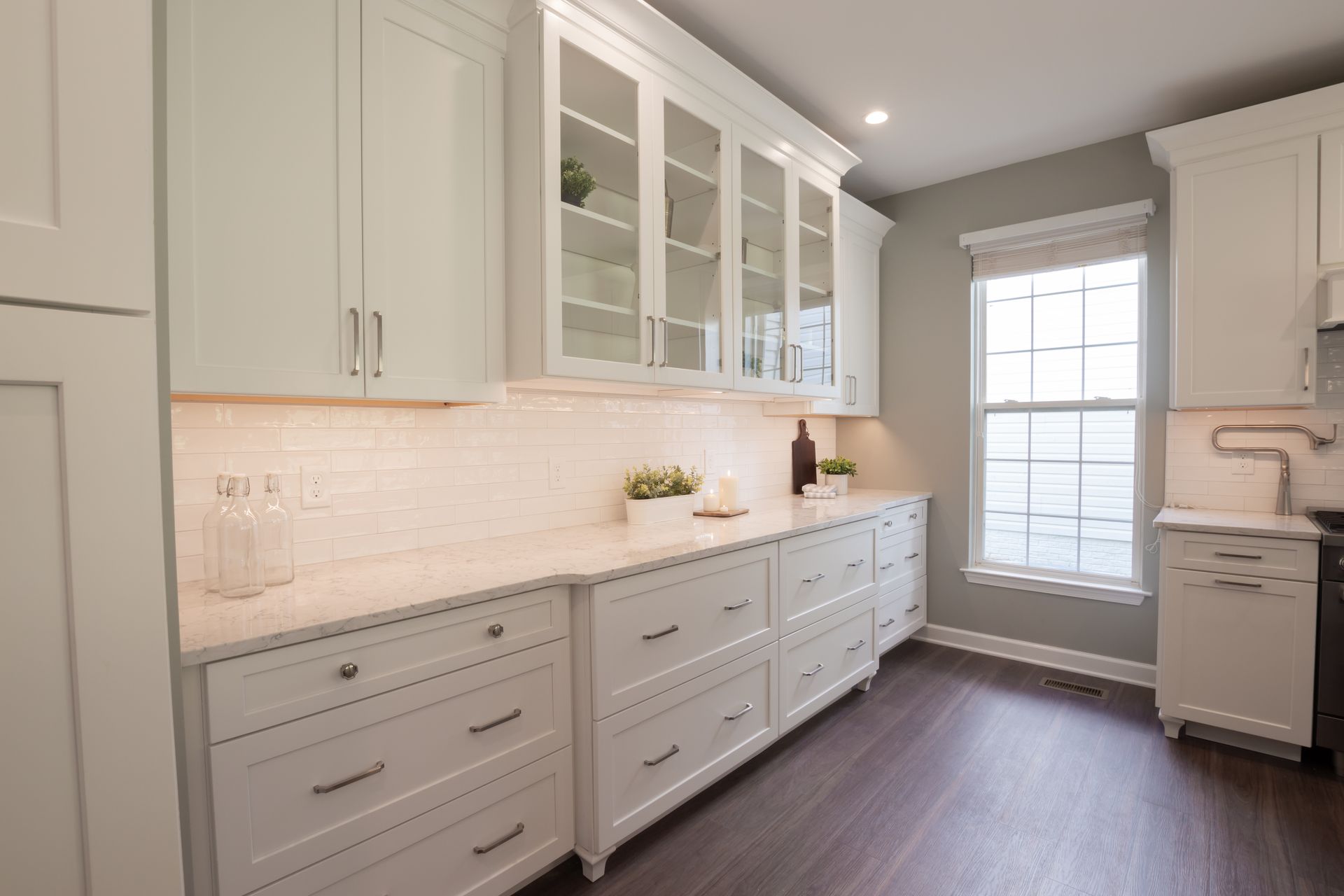 A kitchen with white cabinets and a large window.