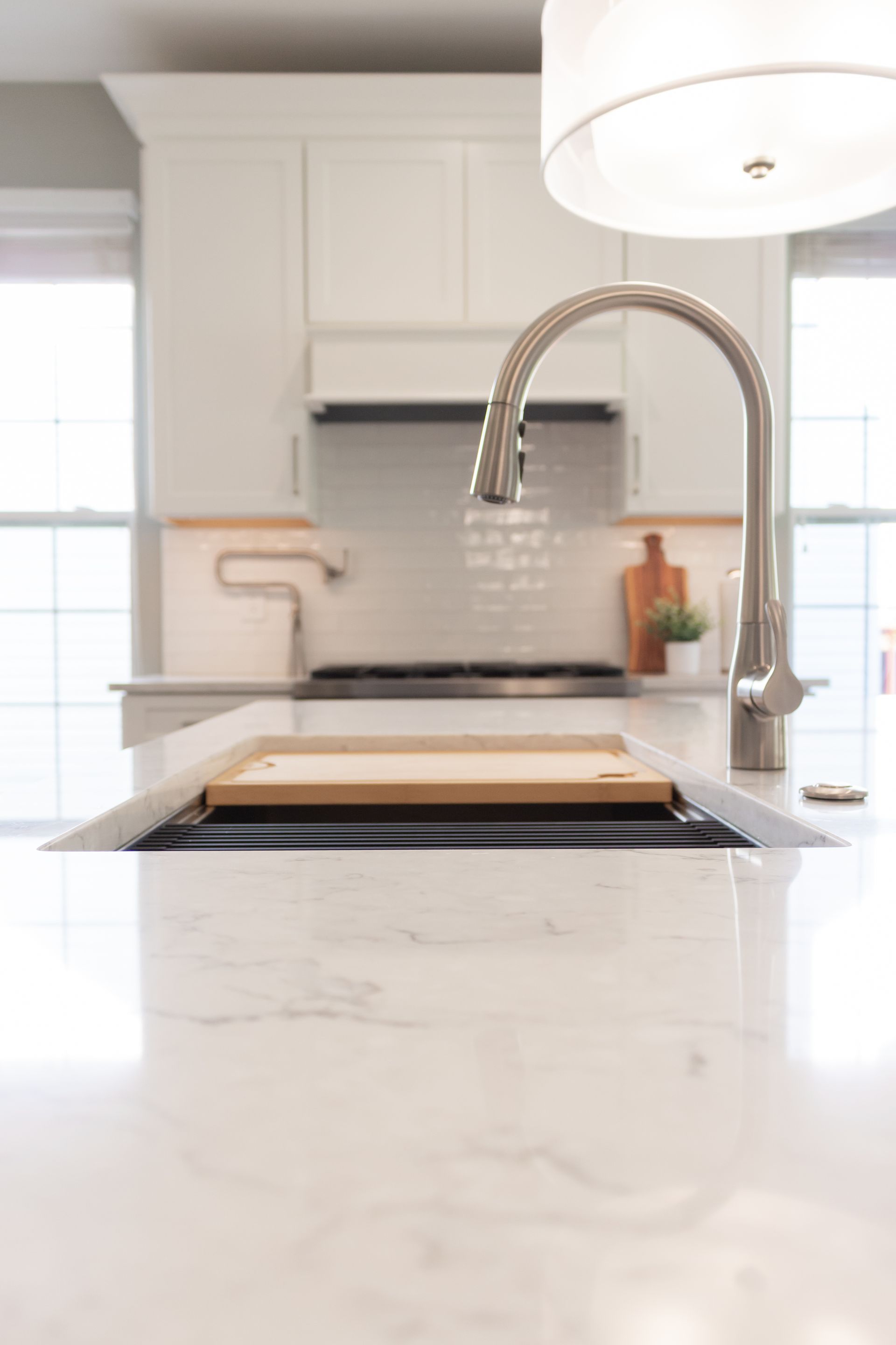 A kitchen sink with a faucet and a cutting board on it.
