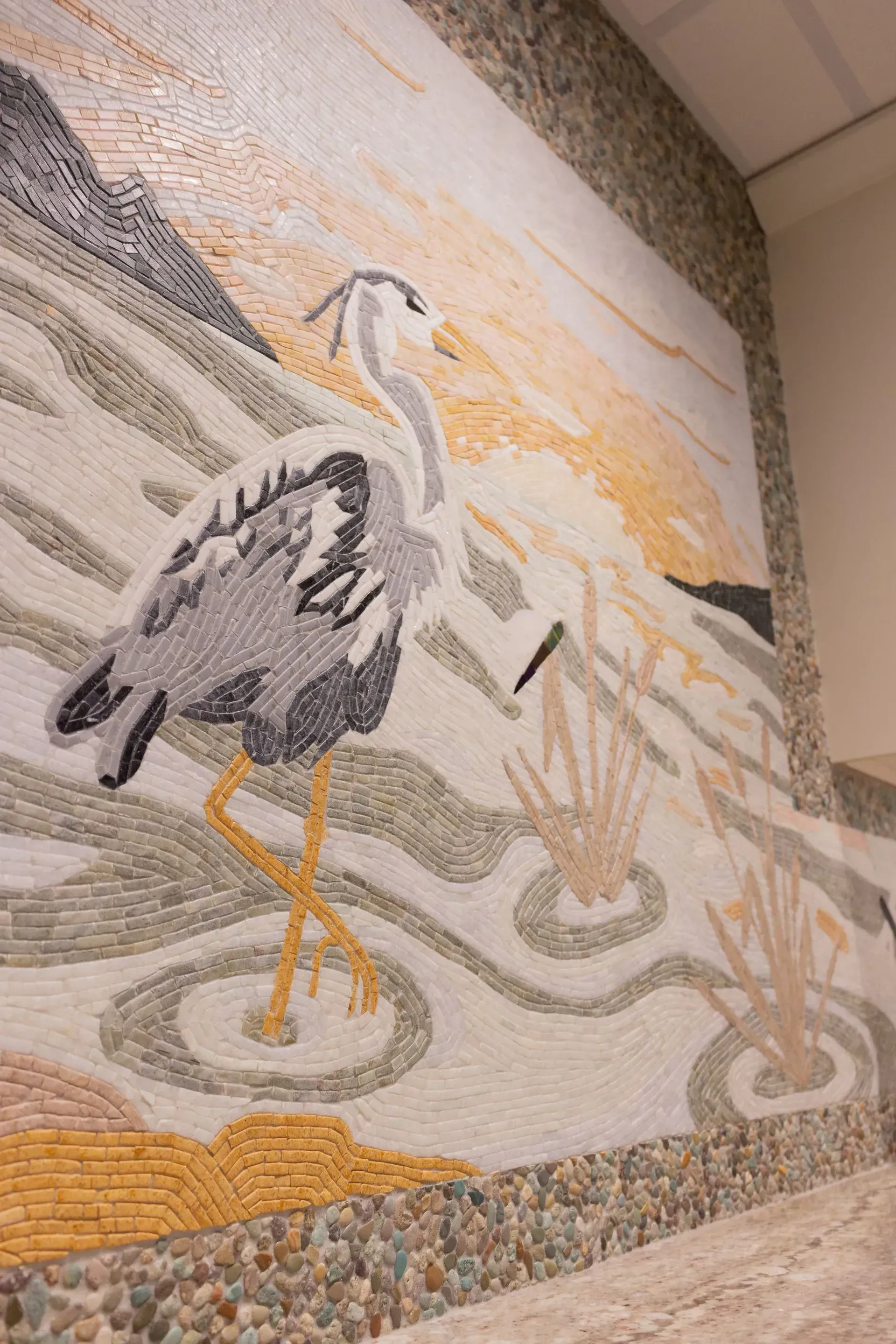A mosaic painting of a bird on a wall.