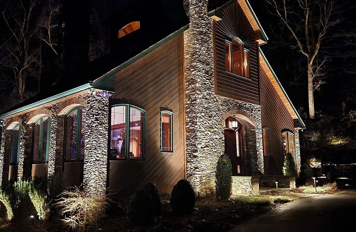 A large stone house is lit up at night.