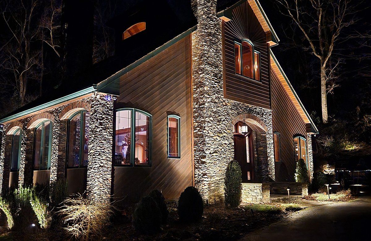 A large stone house is lit up at night.
