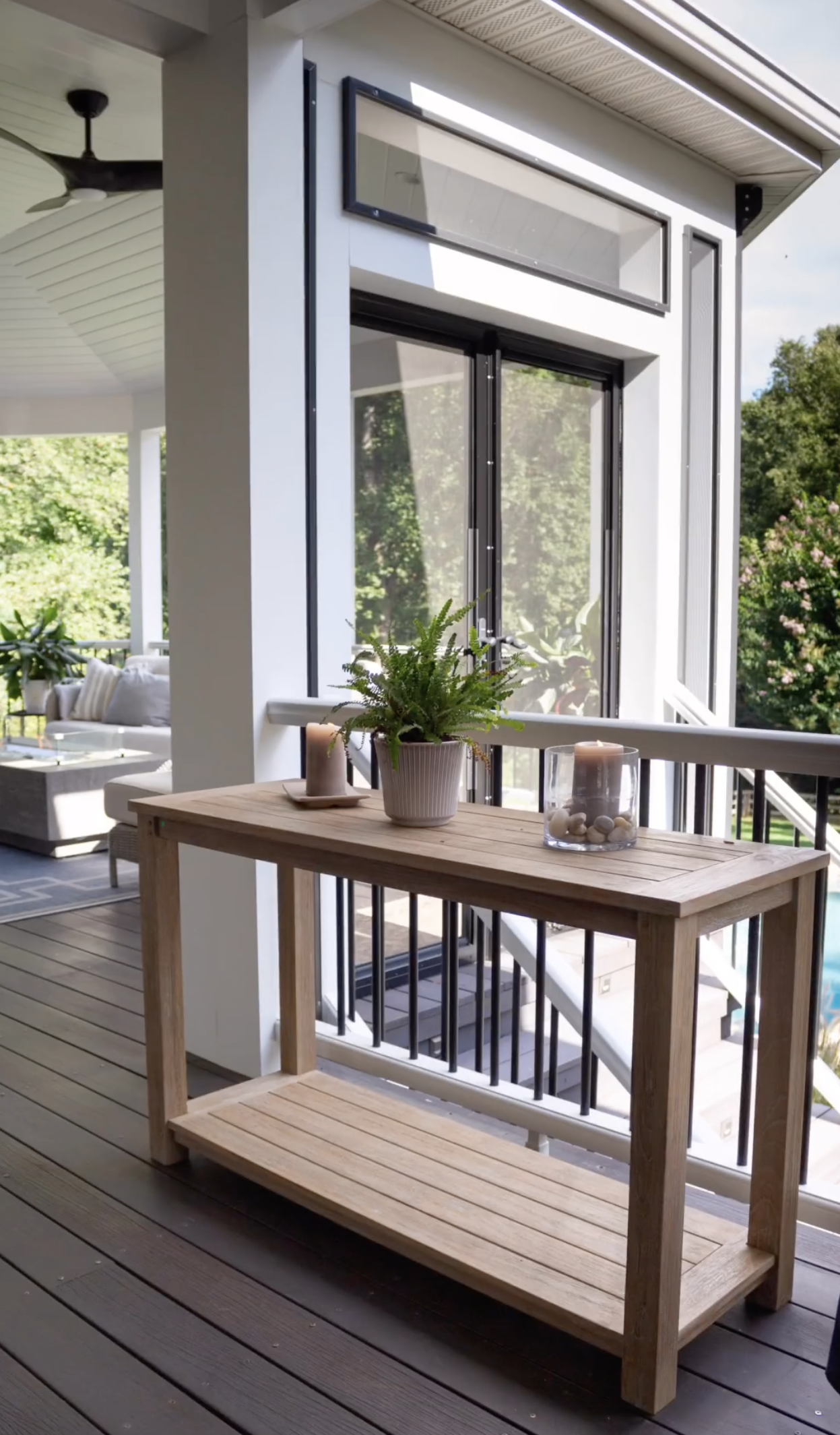 A wooden table is sitting on a deck next to a window.