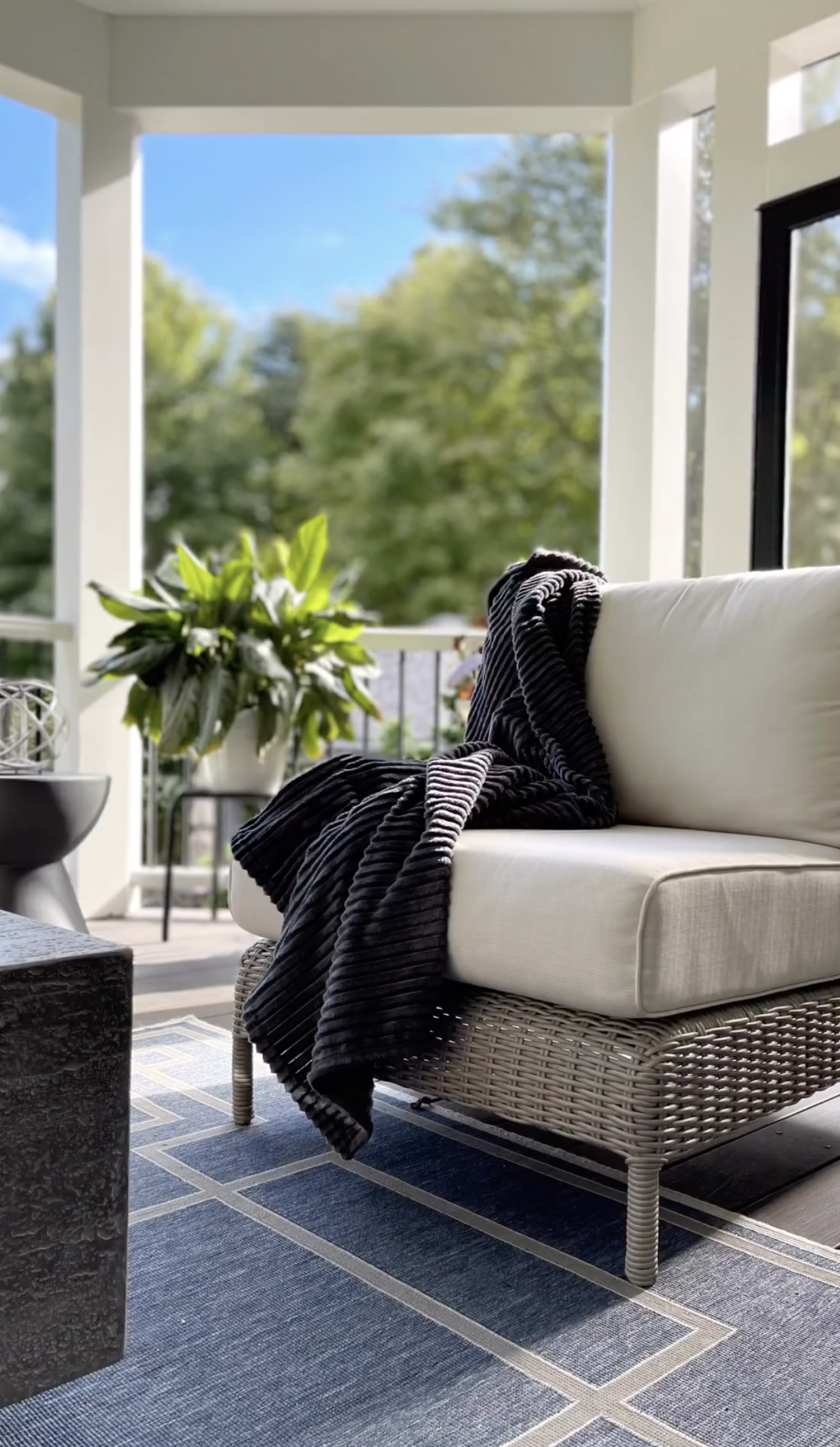 There is a chair with a black blanket on it on the porch.