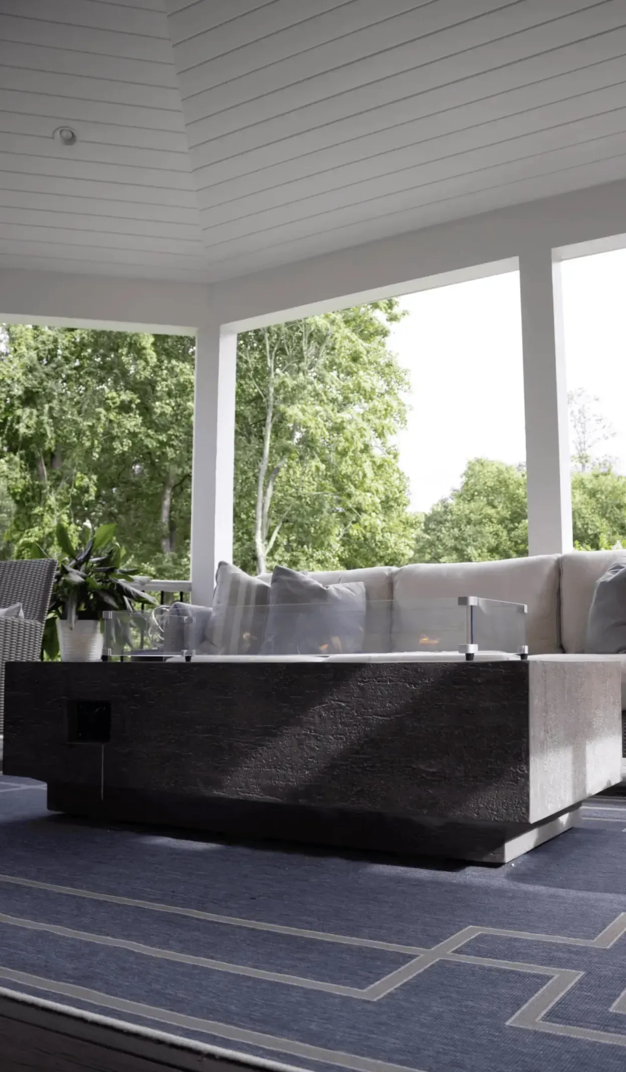 A living room with a couch and a table on a porch.
