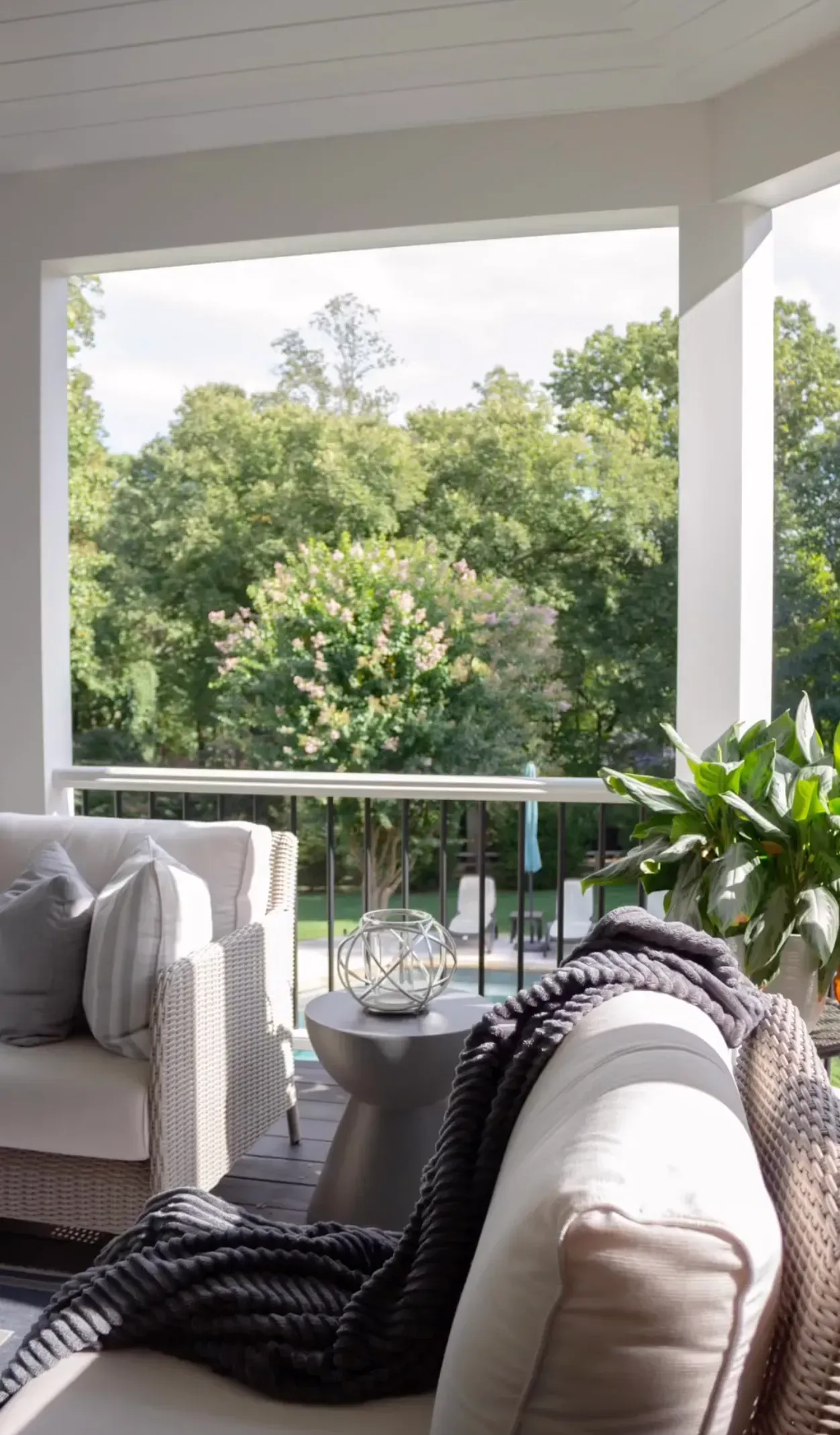 A living room with a couch , chair and table with a view of trees.