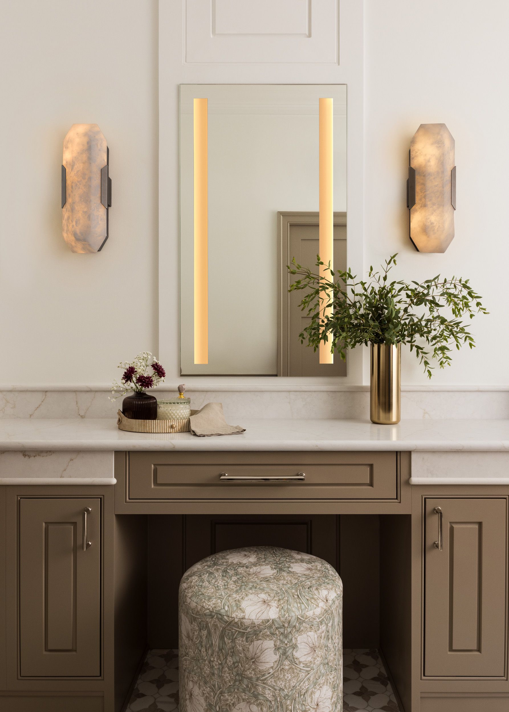 There is a vanity with a mirror and a stool in the bathroom.
