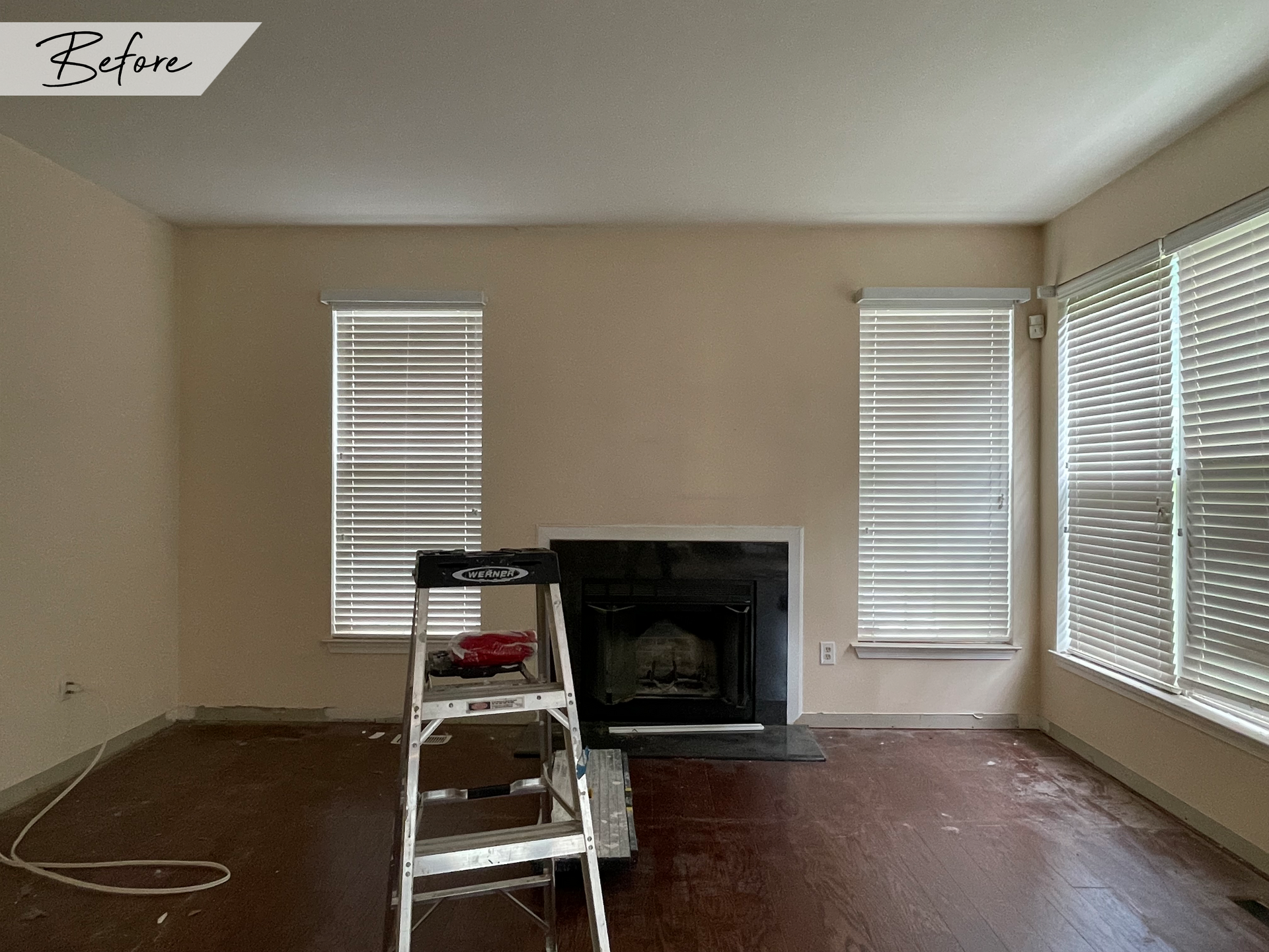 A living room with a fireplace and a ladder in it.