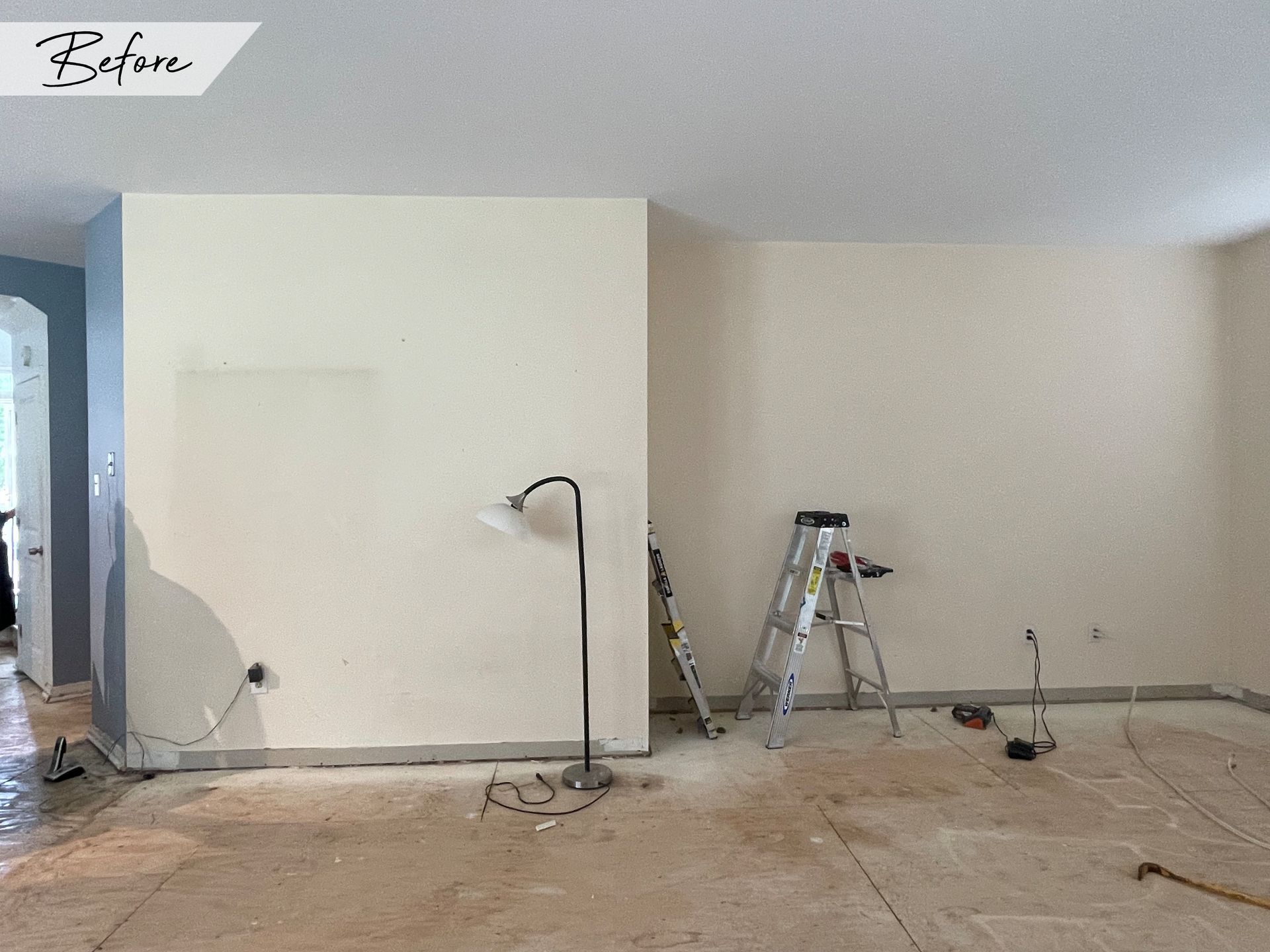 A before picture of a living room with a ladder and a lamp