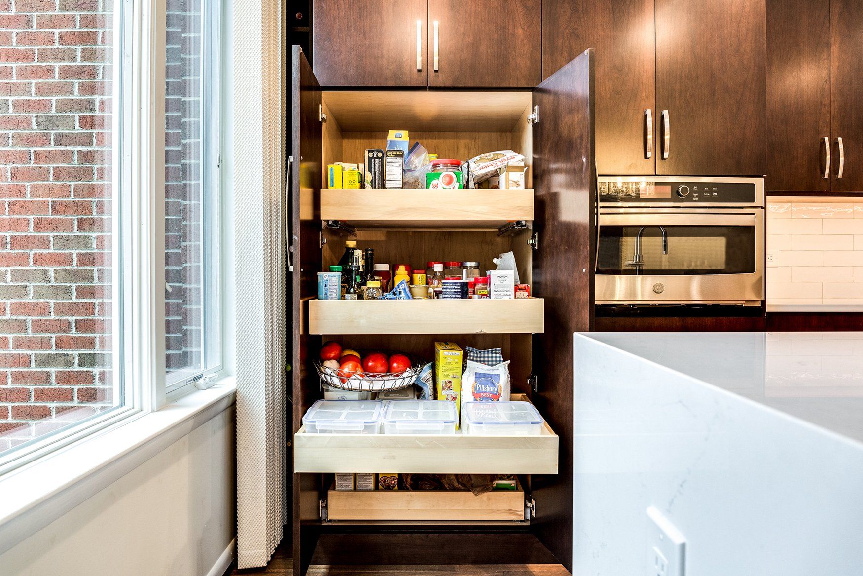 A kitchen with a pantry filled with food and a window.