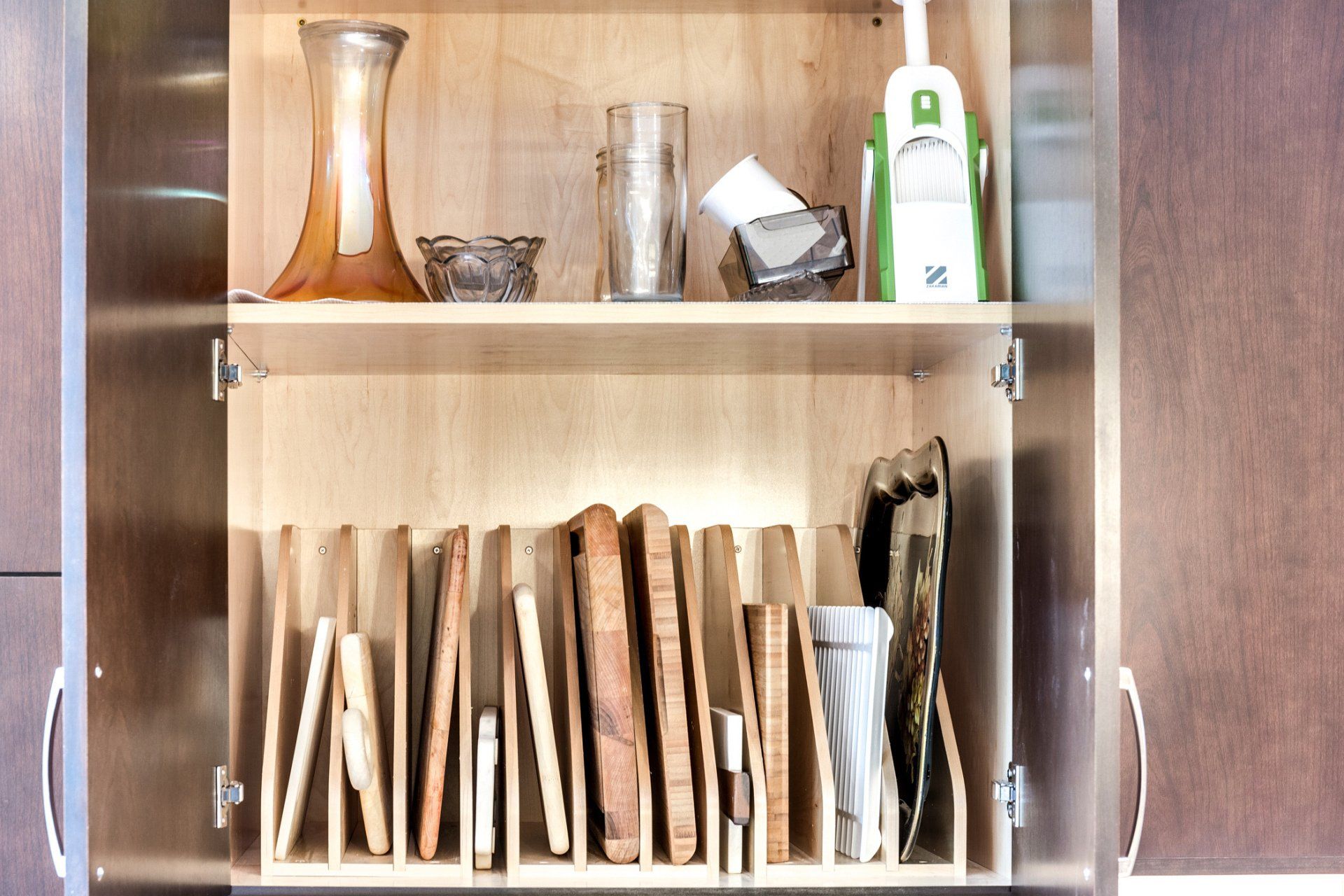 A kitchen cabinet filled with utensils and a vase