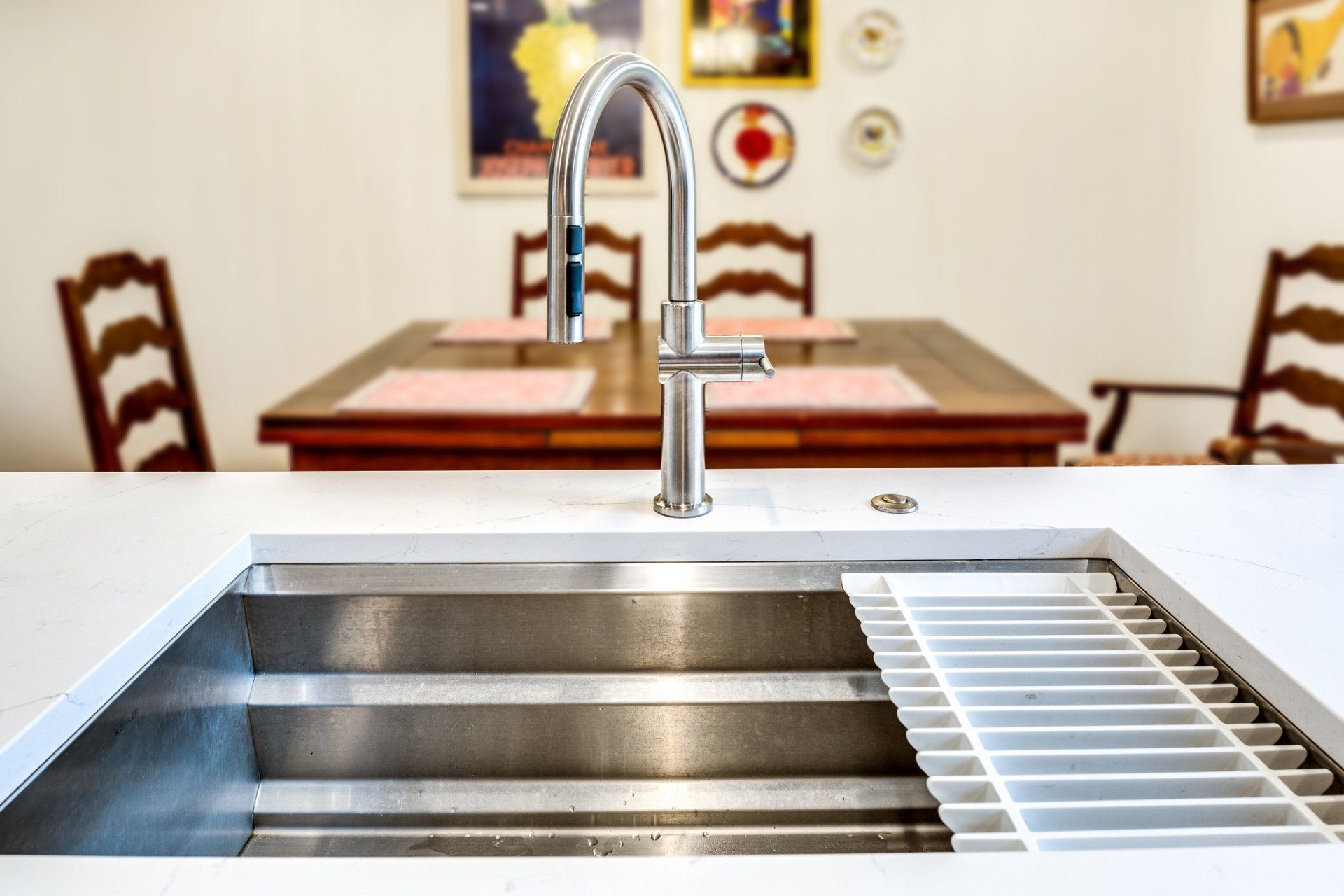 A kitchen sink in front of a dining room table and chairs.