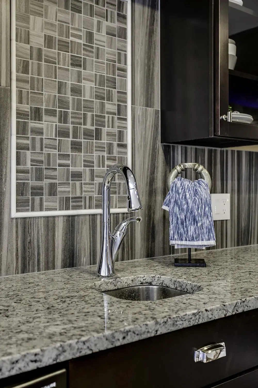 A kitchen sink with a faucet and a towel hanging on the counter.