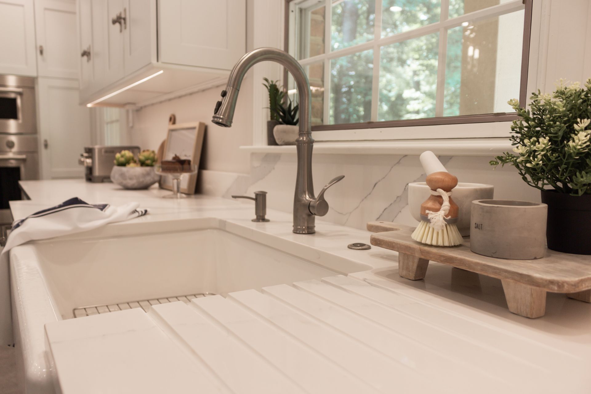 A kitchen sink with a faucet and a window in the background.