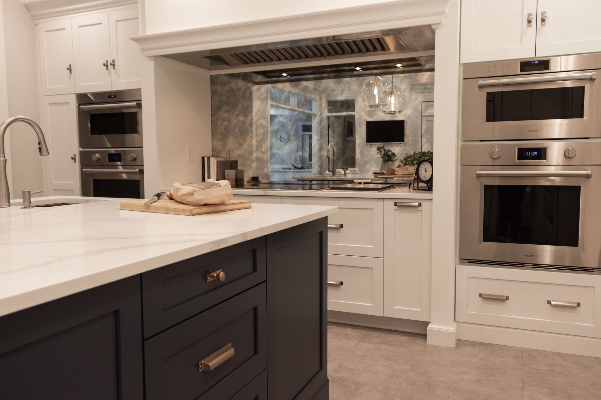 A kitchen with blue cabinets , white cabinets , stainless steel appliances and a large island.