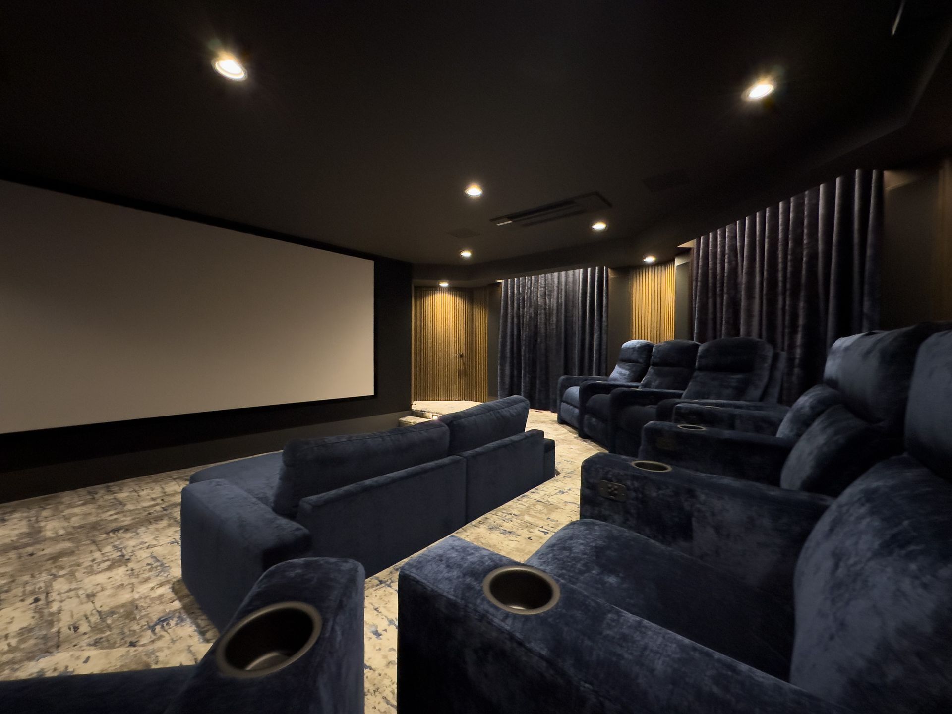 A home theater with blue chairs and a large screen.