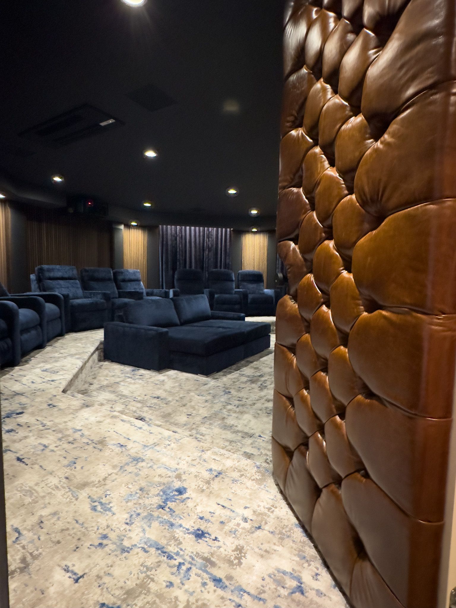 A living room with a couch , chairs , and a leather wall.