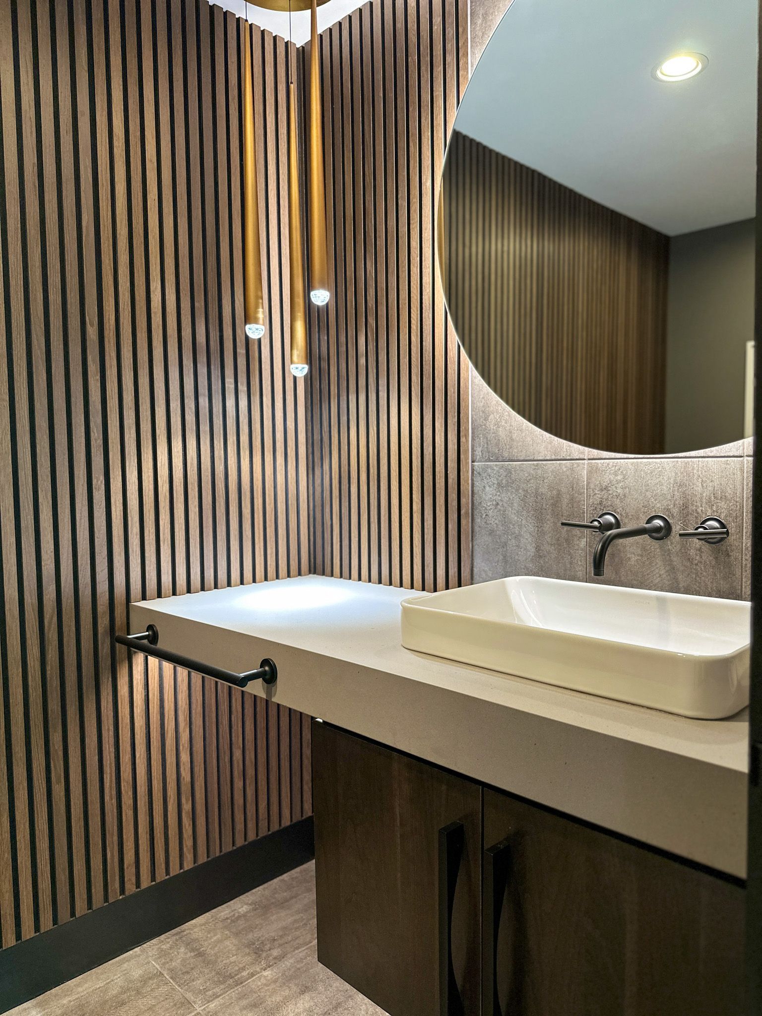 A bathroom with a sink , mirror and wooden wall.