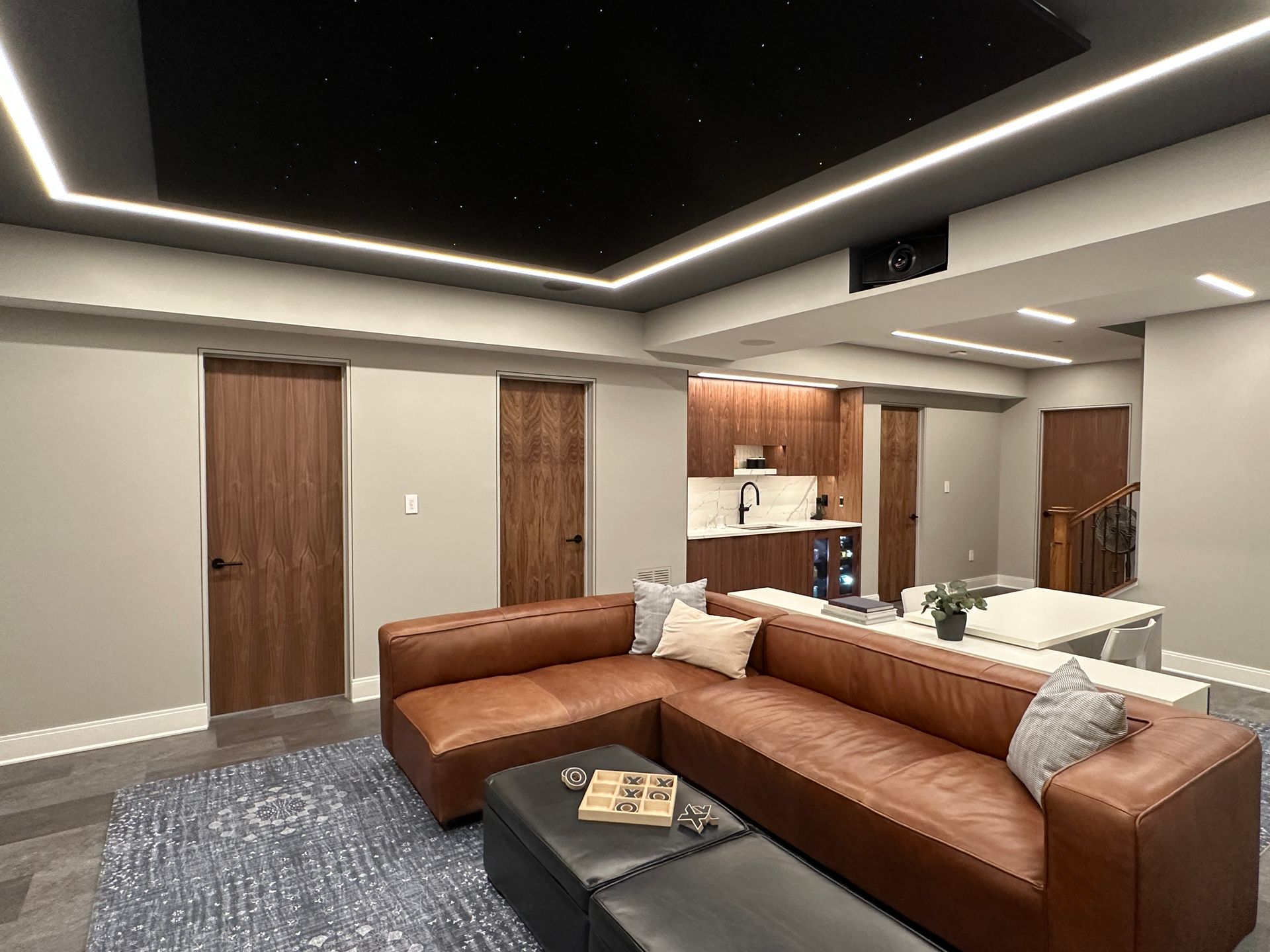 A living room with a brown couch and a black ottoman.
