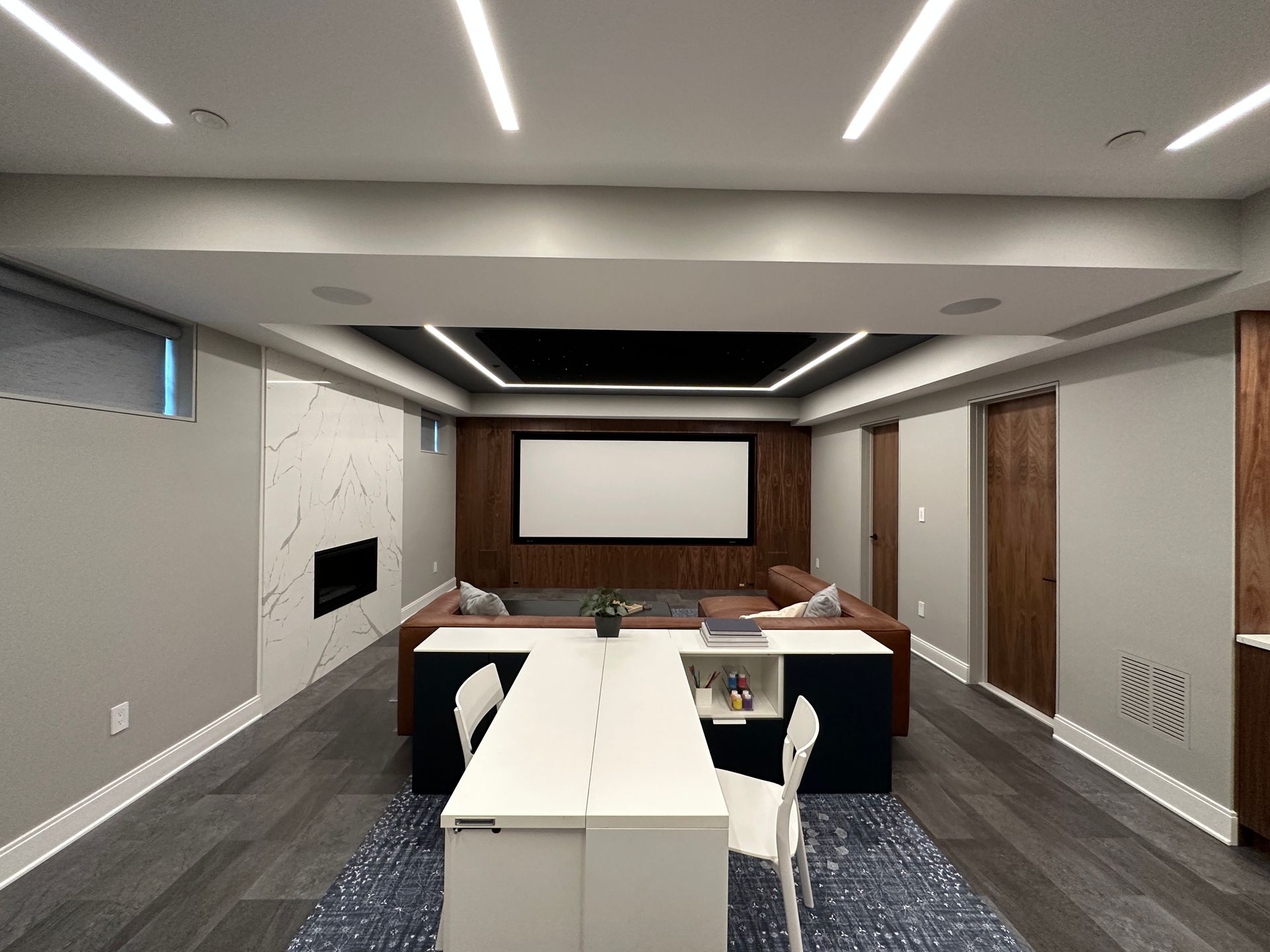 A basement with a projector screen and a desk.