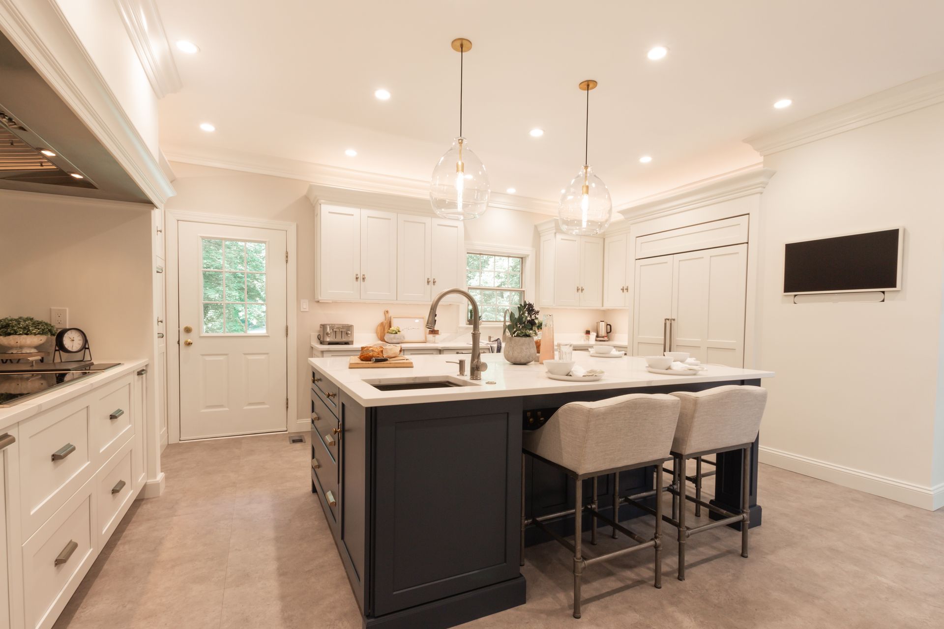 A kitchen with a large island , stools , a sink and a television.
