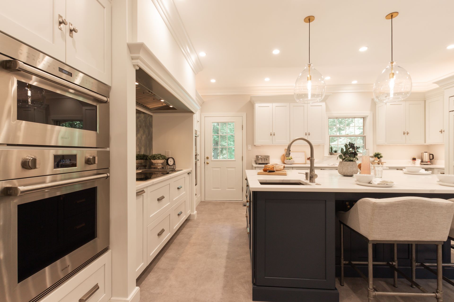 A kitchen with white cabinets , stainless steel appliances , a large island and a sink.