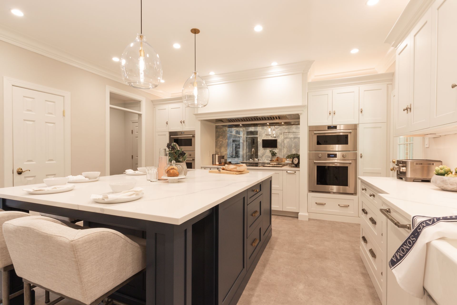 A kitchen with white cabinets and stainless steel appliances and a large island.