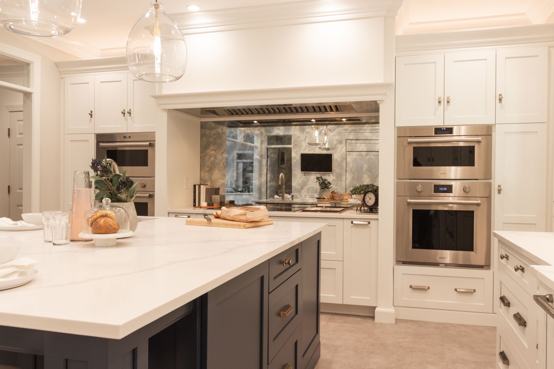 A kitchen with white cabinets , stainless steel appliances , and a large island.