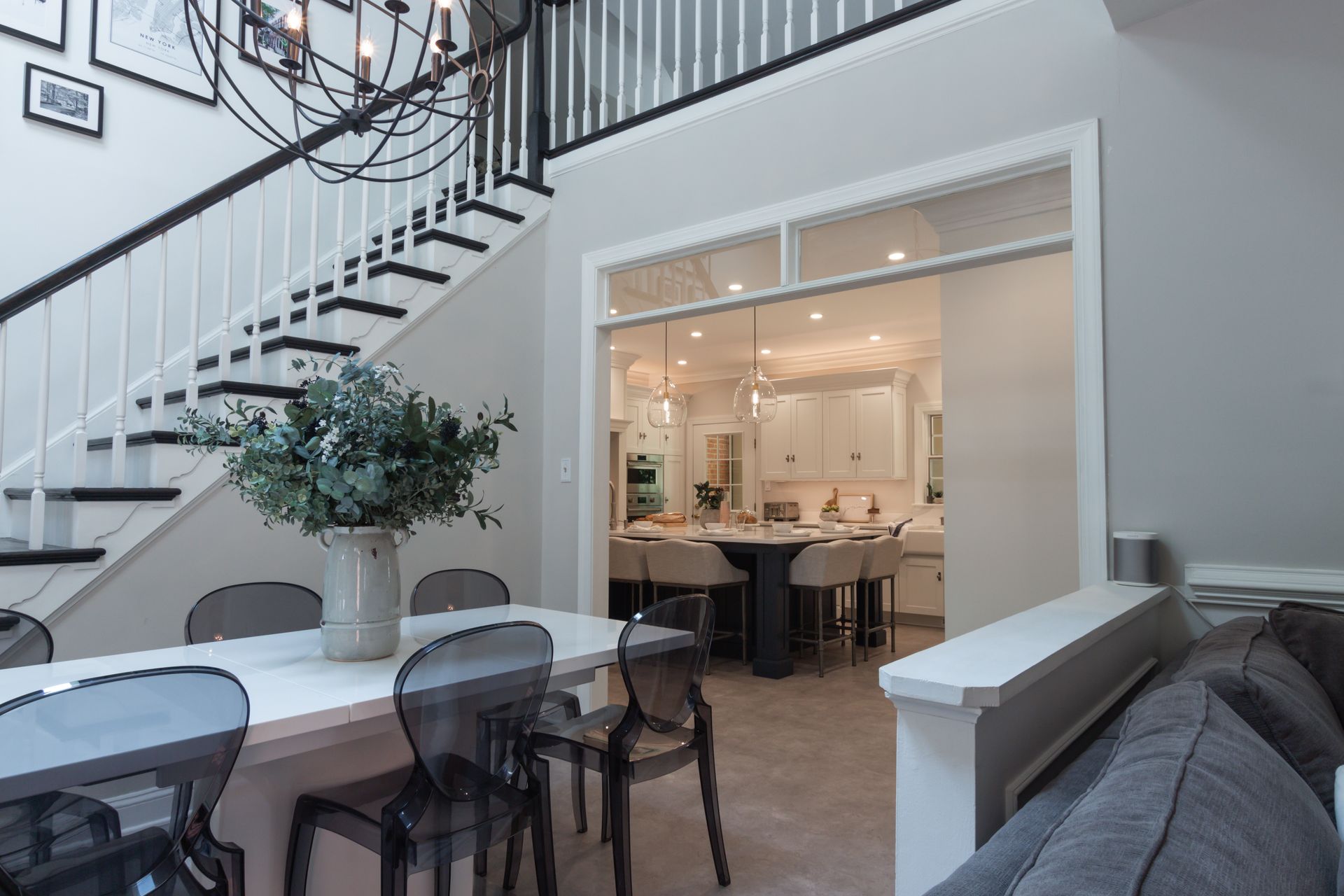 A dining room with a table and chairs and a staircase leading to the kitchen.