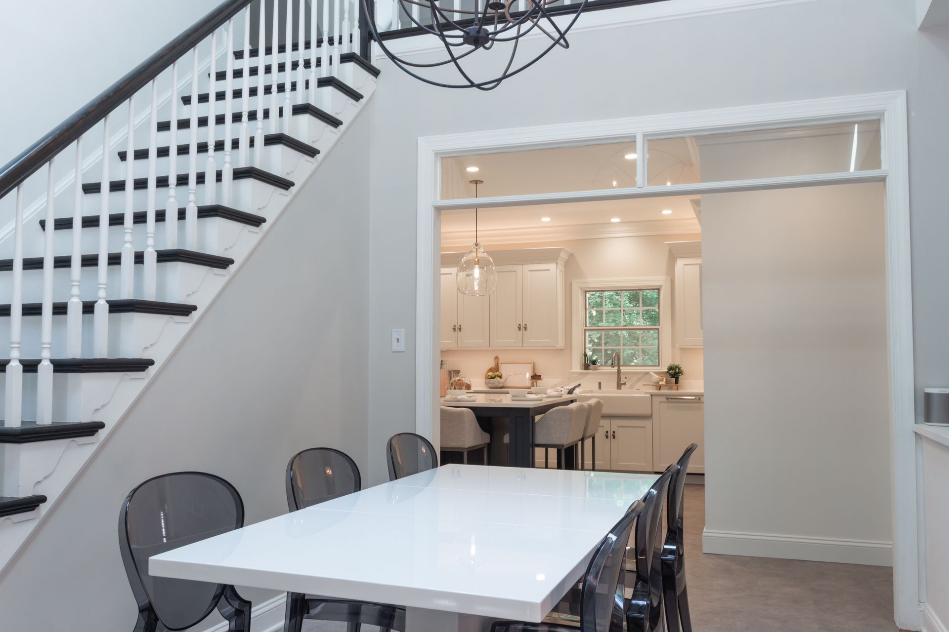A dining room with a table and chairs and stairs leading to a kitchen.