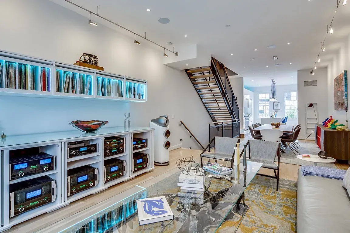 A living room with a glass coffee table and a staircase leading to the second floor.