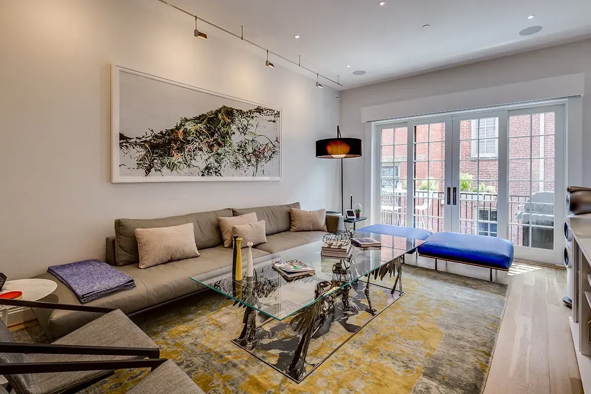 A living room with a couch , coffee table , chairs and a painting on the wall.