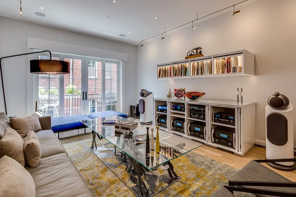 A living room with a couch , coffee table , speakers and shelves.