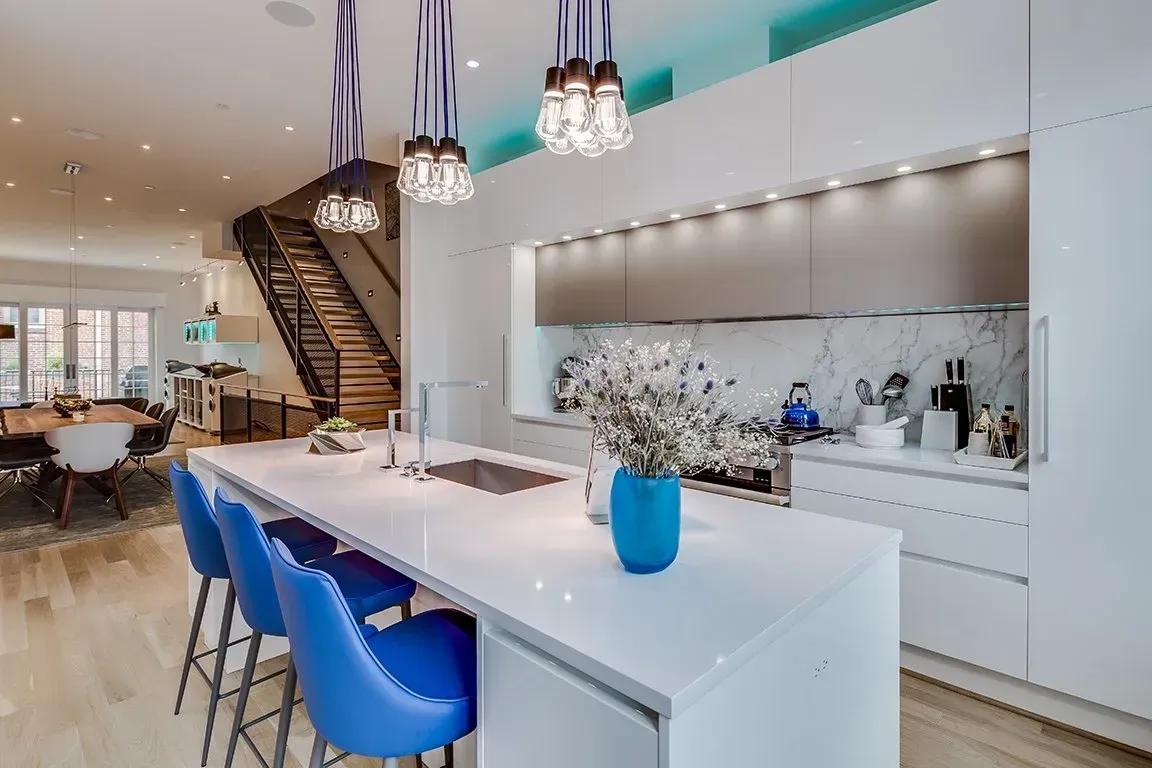 A kitchen with a large island and blue chairs.