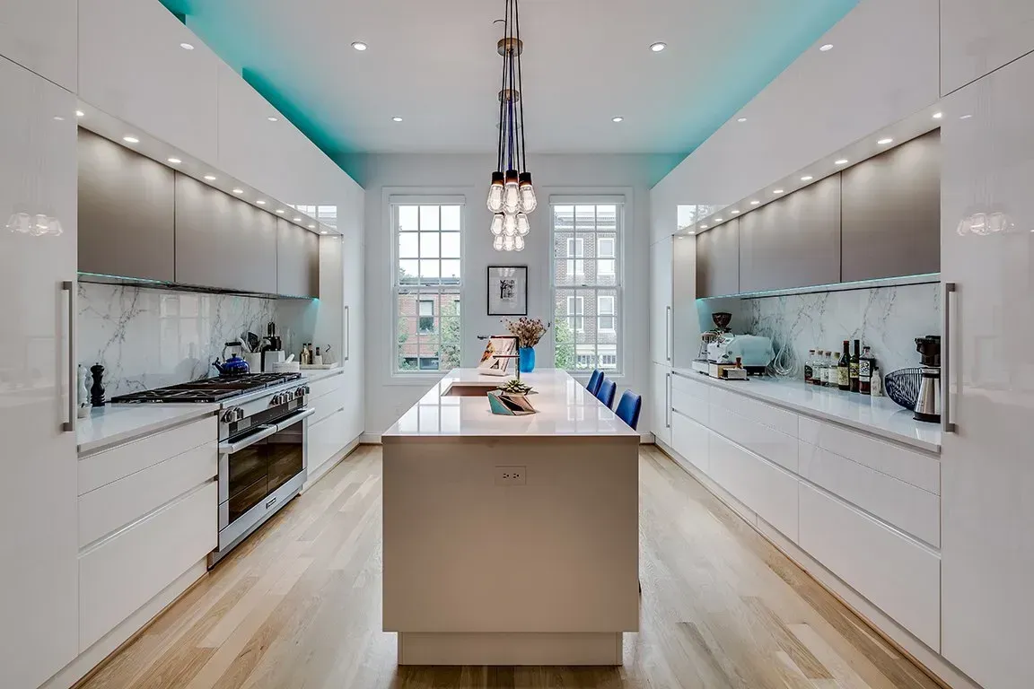 A kitchen with white cabinets and a large island in the middle