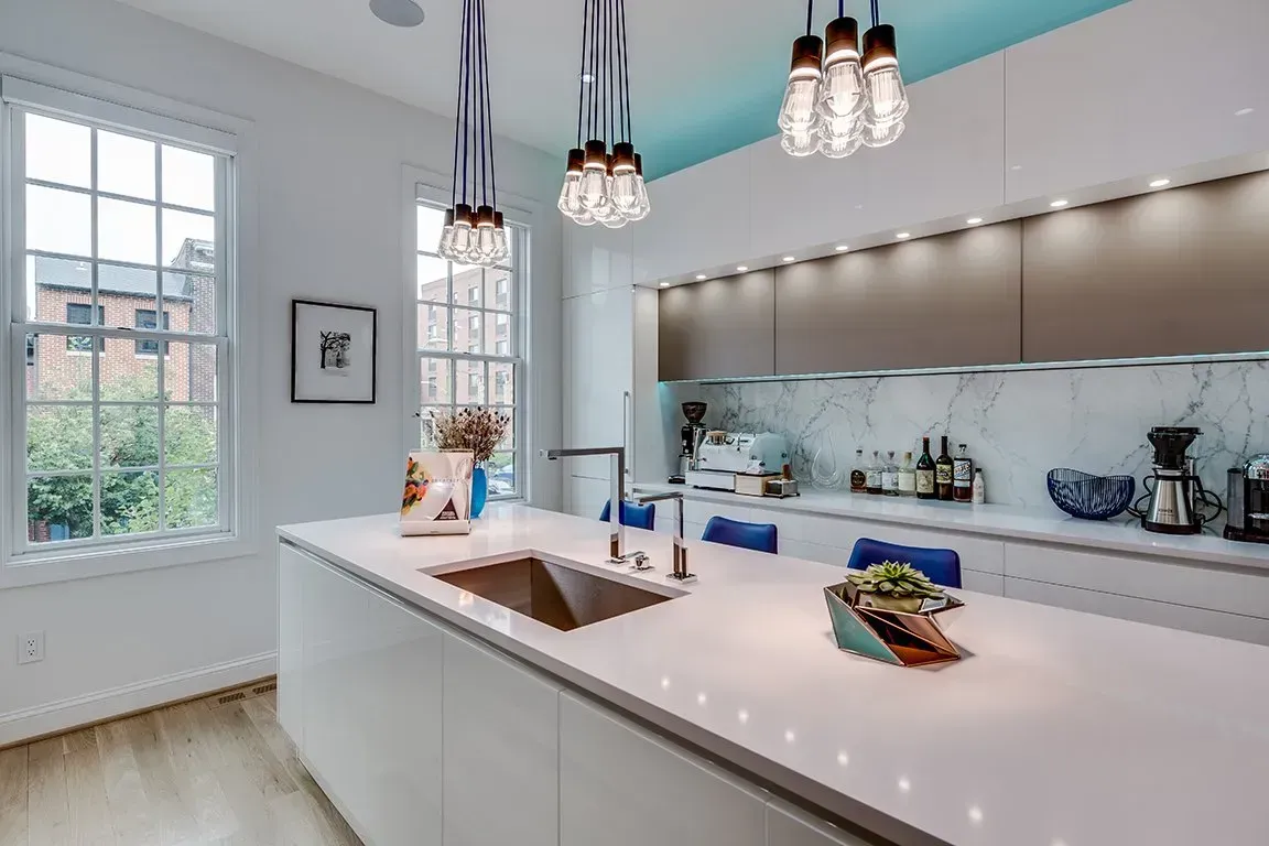 A kitchen with white cabinets , a sink , and a window.