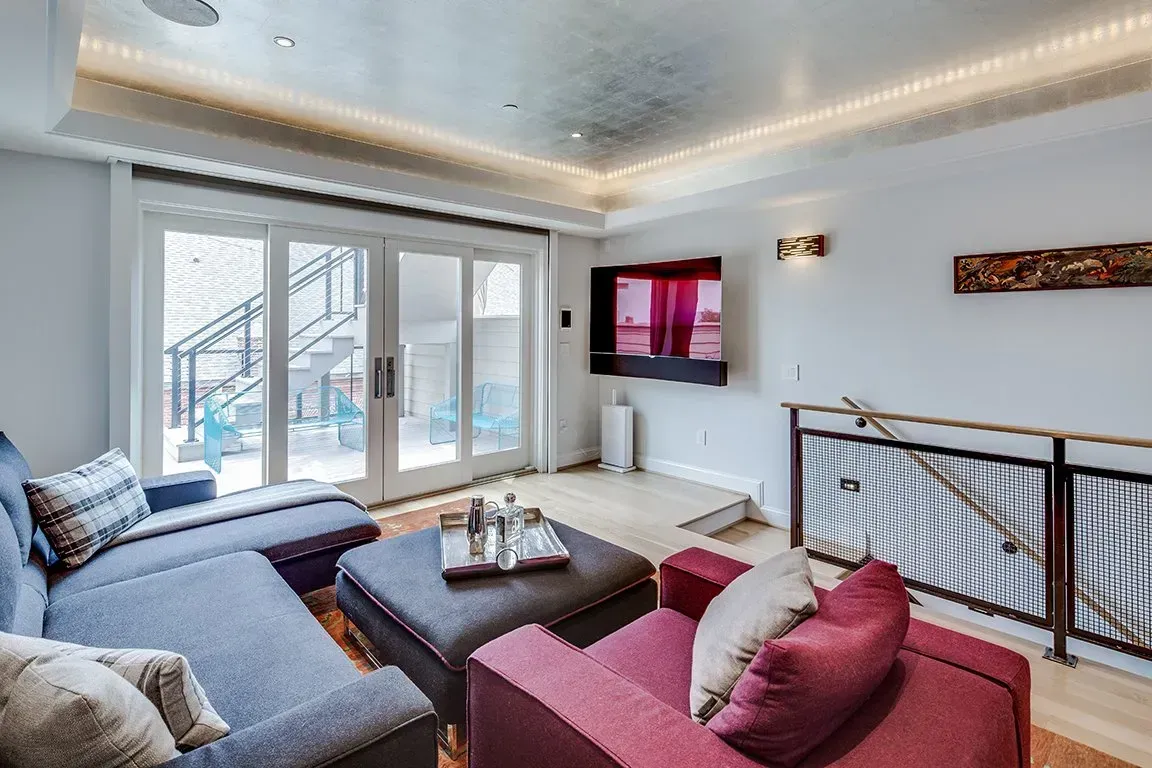 A living room with a couch , chair , ottoman and television.