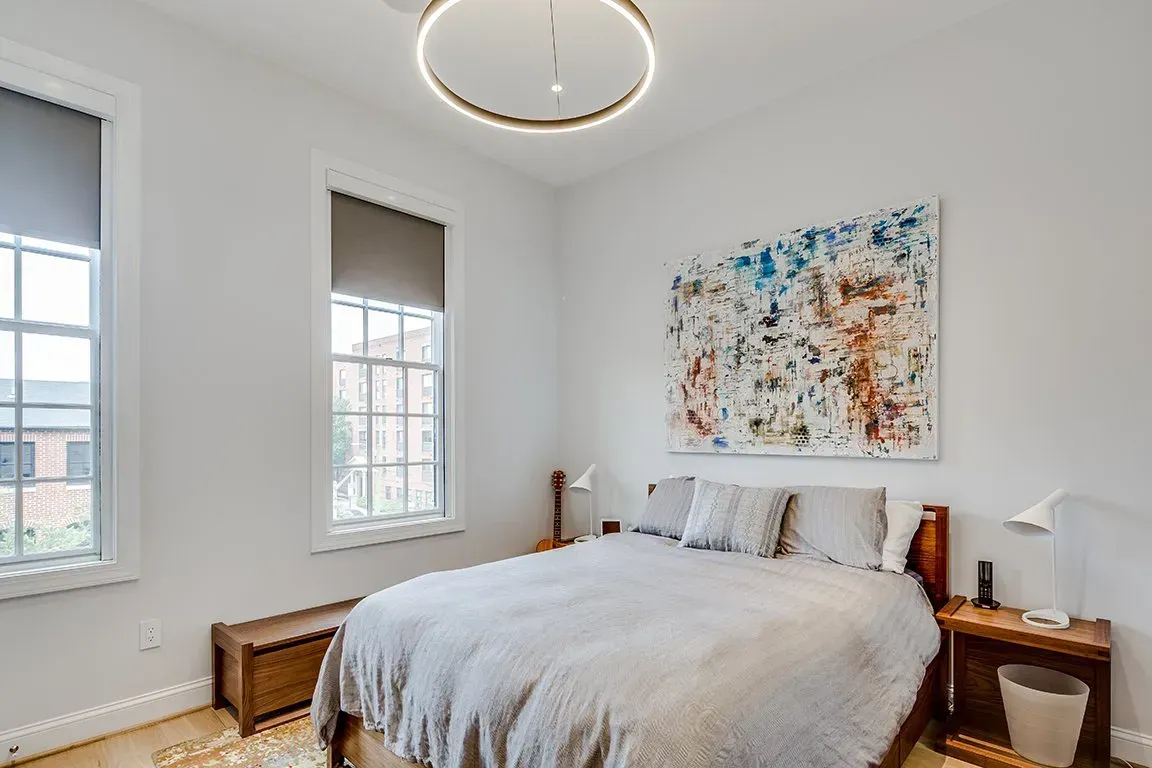 A bedroom with a large bed and a painting on the wall.