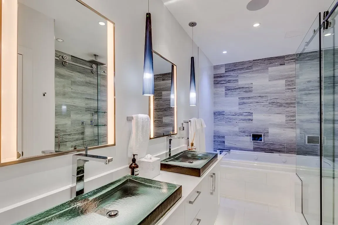 A bathroom with two sinks , two mirrors and a tub.