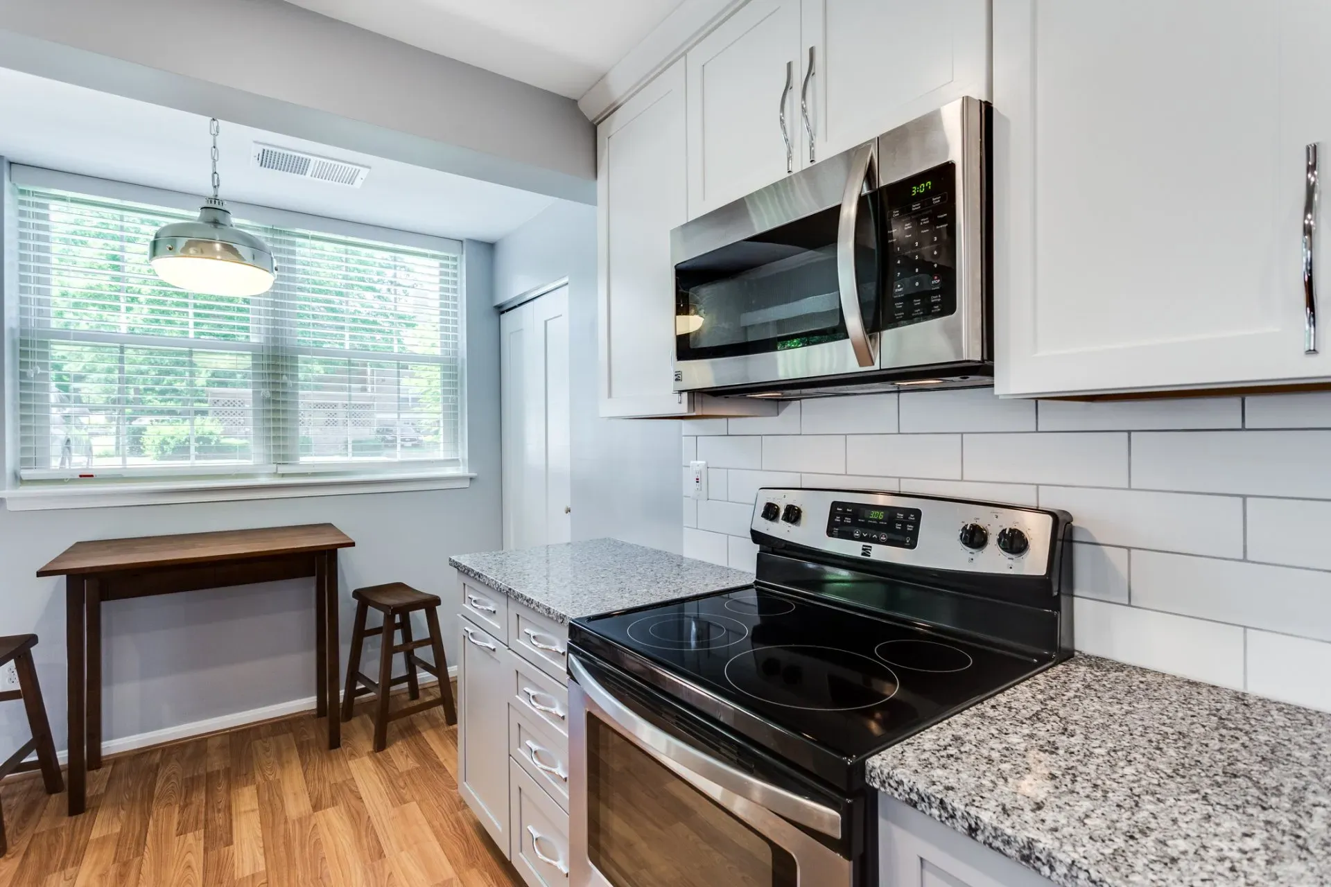 A kitchen with stainless steel appliances , granite counter tops , and white cabinets.